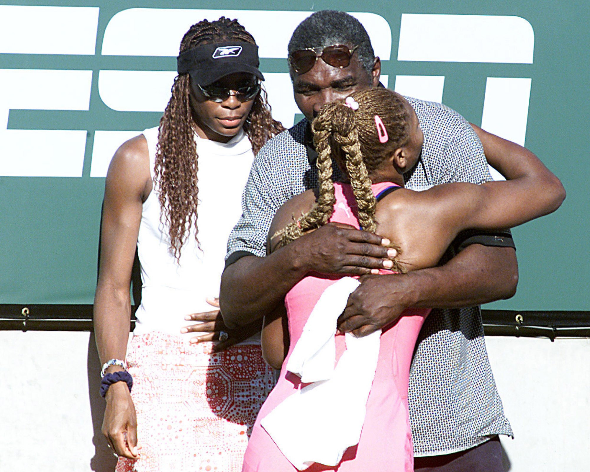 Serena Williams of the US hugs her father Richard as her sister Venus waits in the back after her victory over Kim Clijsters of Belgium during the final of the Tennis Masters Series at Indian Wells, California, in 2001. Photo: Allsport