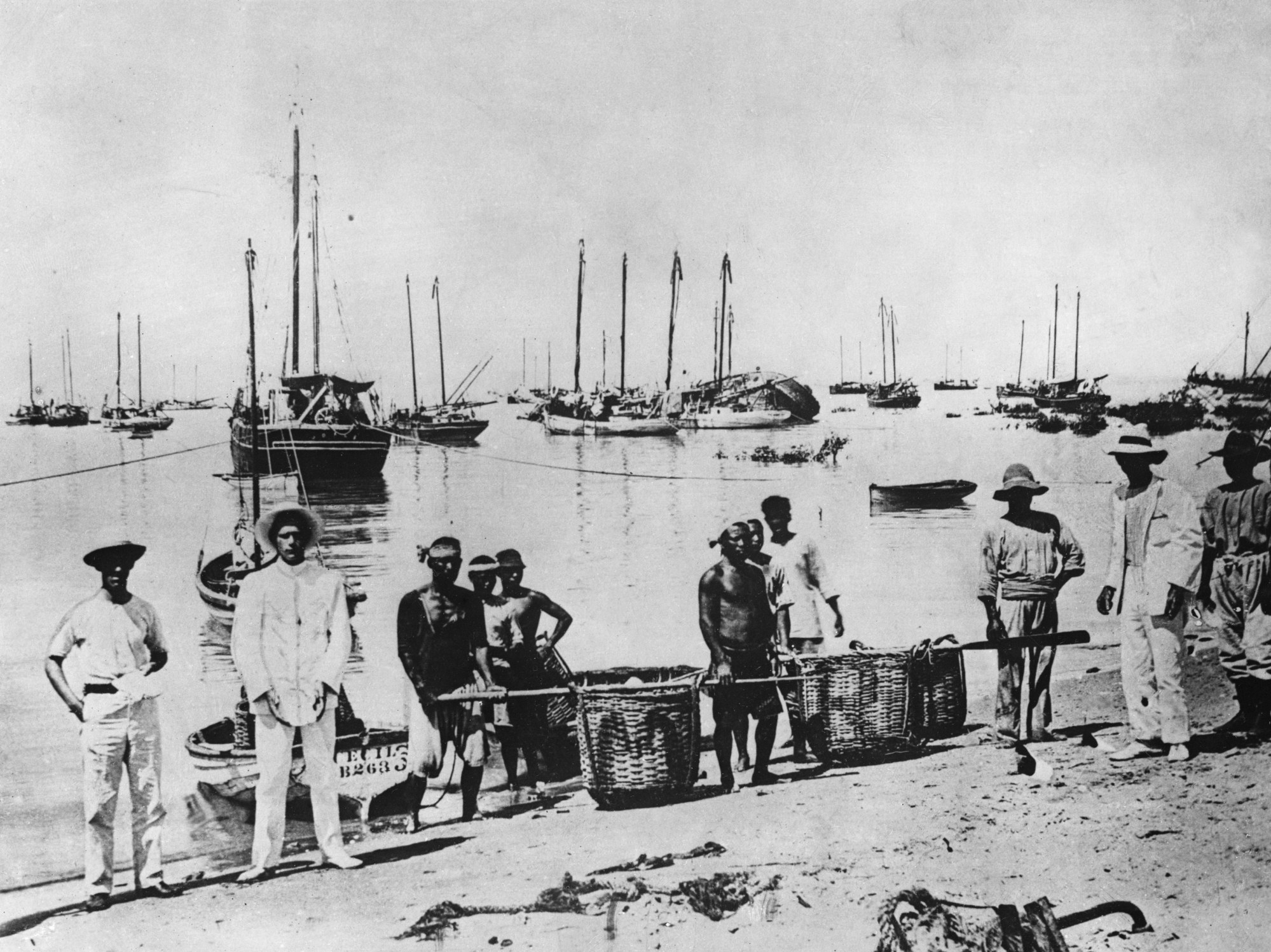 Men carry baskets of shells containing mother-of-pearl onto a beach at Broome in this undated photo from the 1900s. Photo: Getty Images