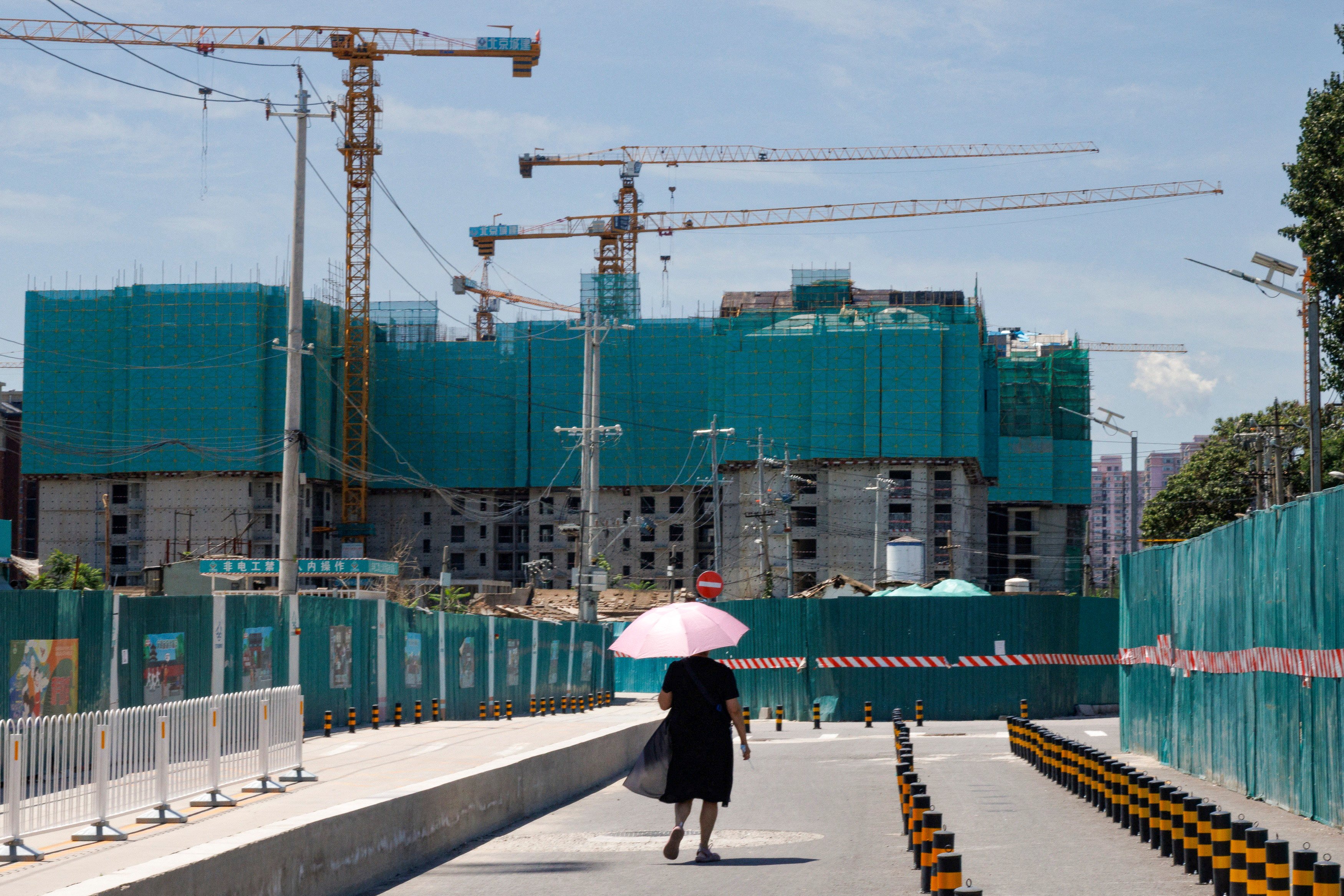 A woman walks near a construction site of apartment buildings in Beijing. Photo: Reuters