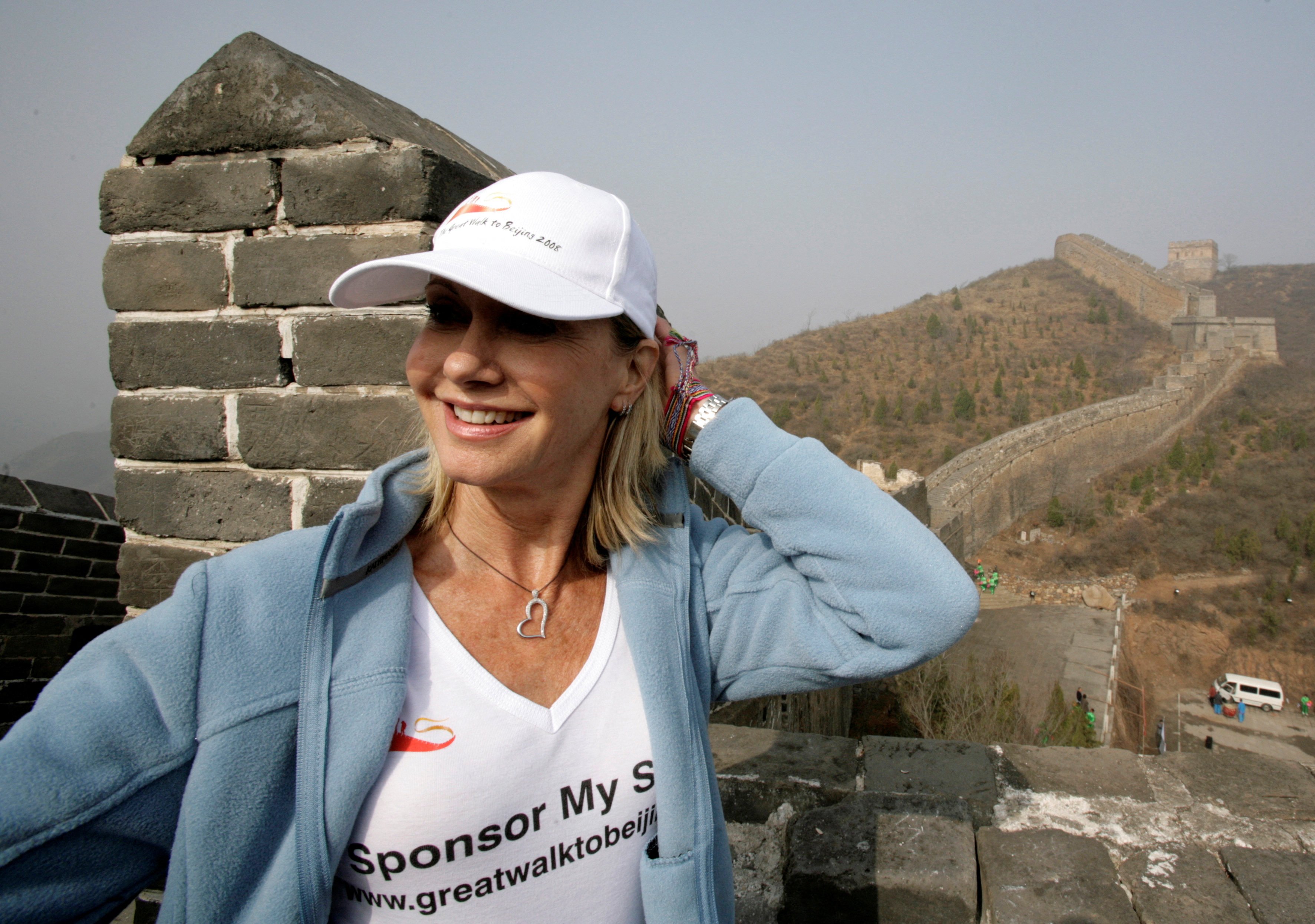The late Olivia Newton-John stands at the Jinshanling section of the Great Wall of China in Hebei province, April 7, 2008 at the start of the “Great Walk to Beijing”, which she initiated to raise funds to build the Olivia Newton-John Cancer Centre in Melbourne, Australia. Photo: Reuters