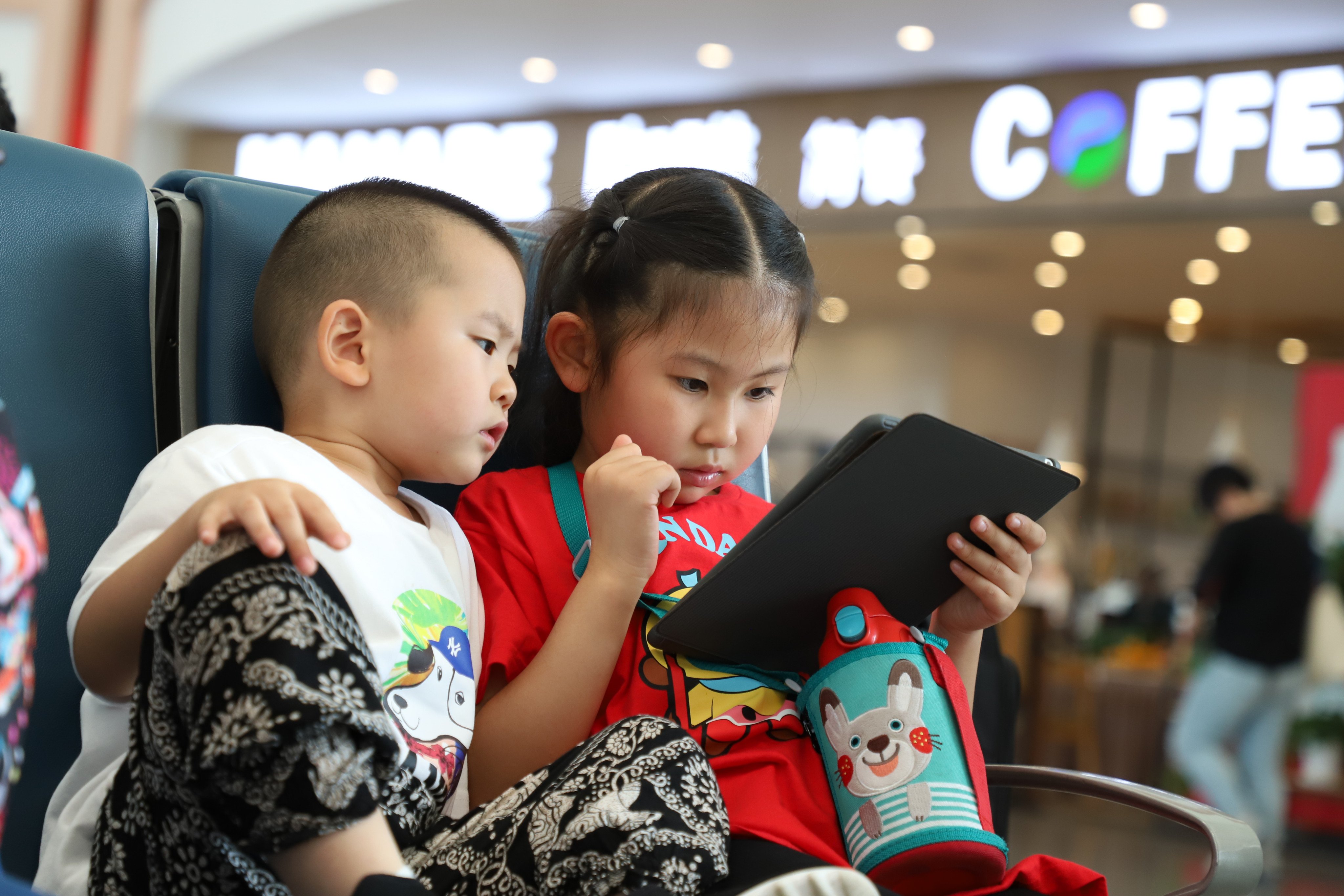 Two children play video games on a tablet at an airport in Xian, China. Photo: Shutterstock