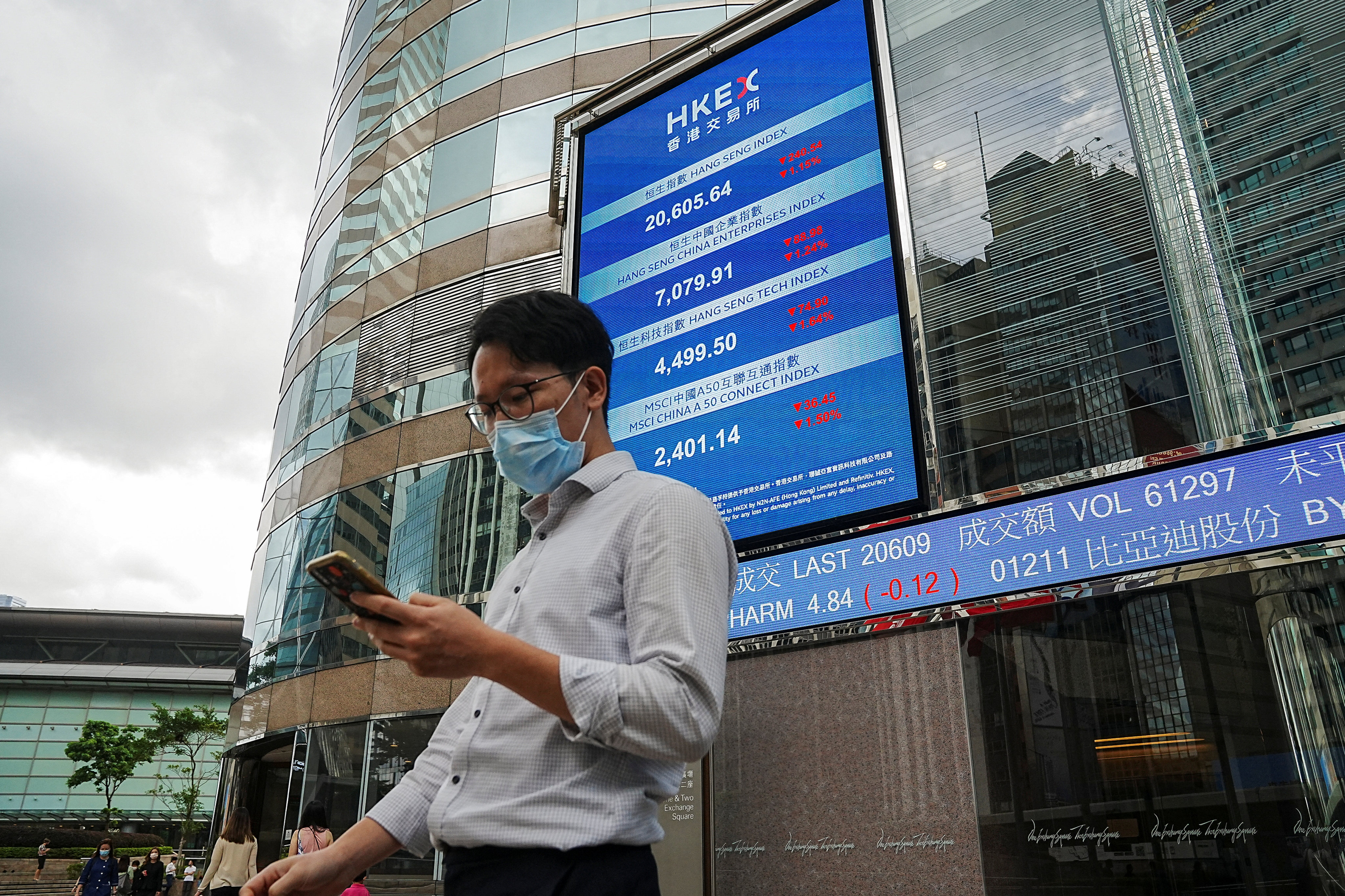 People walk past a screen displaying the Hang Seng stock index outside Hong Kong stock exchange. Photo: Lam Yik