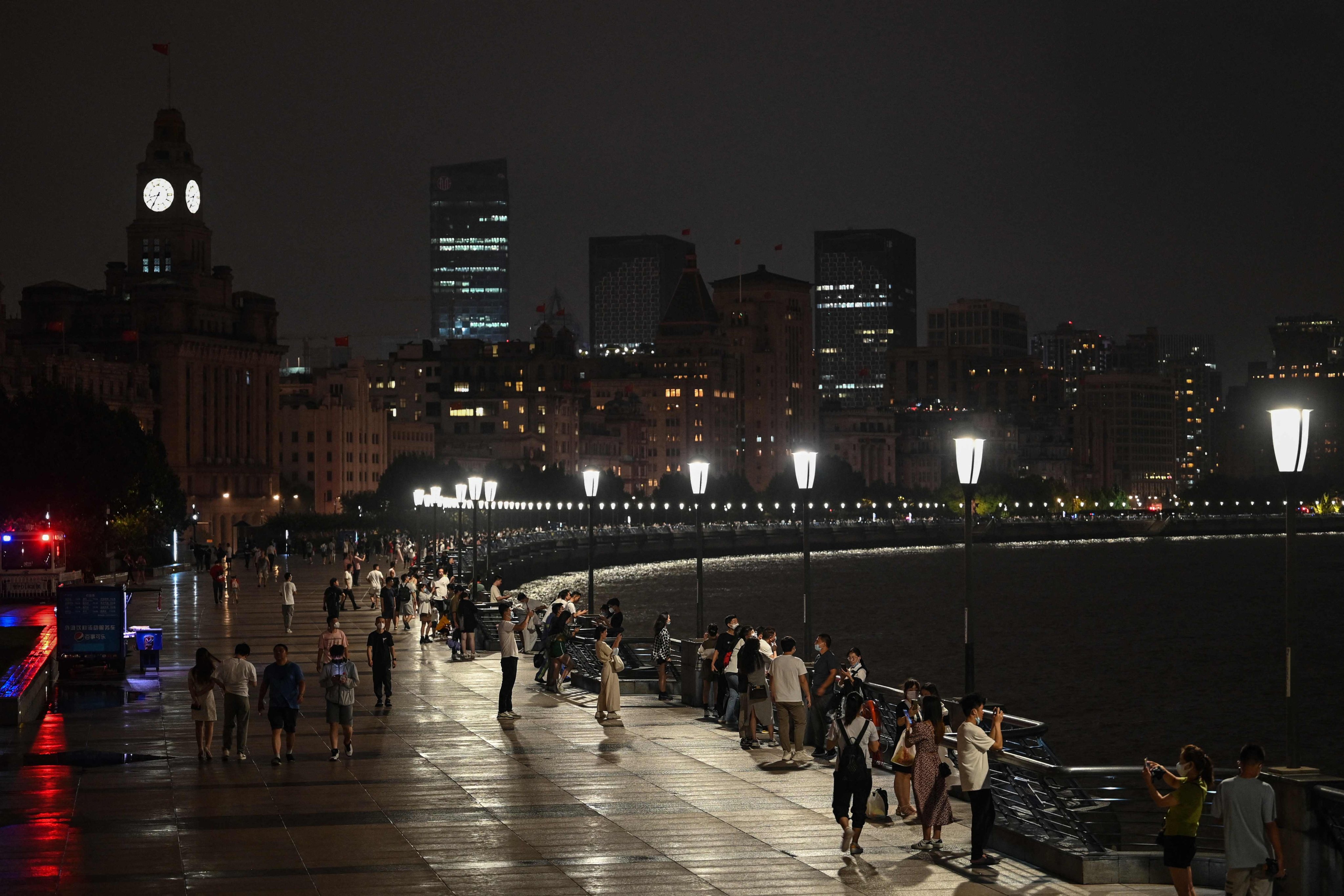 People walk along The Bund promenade as decorative lights are switched off to save energy in Shanghai on Tuesday. Photo: AFP