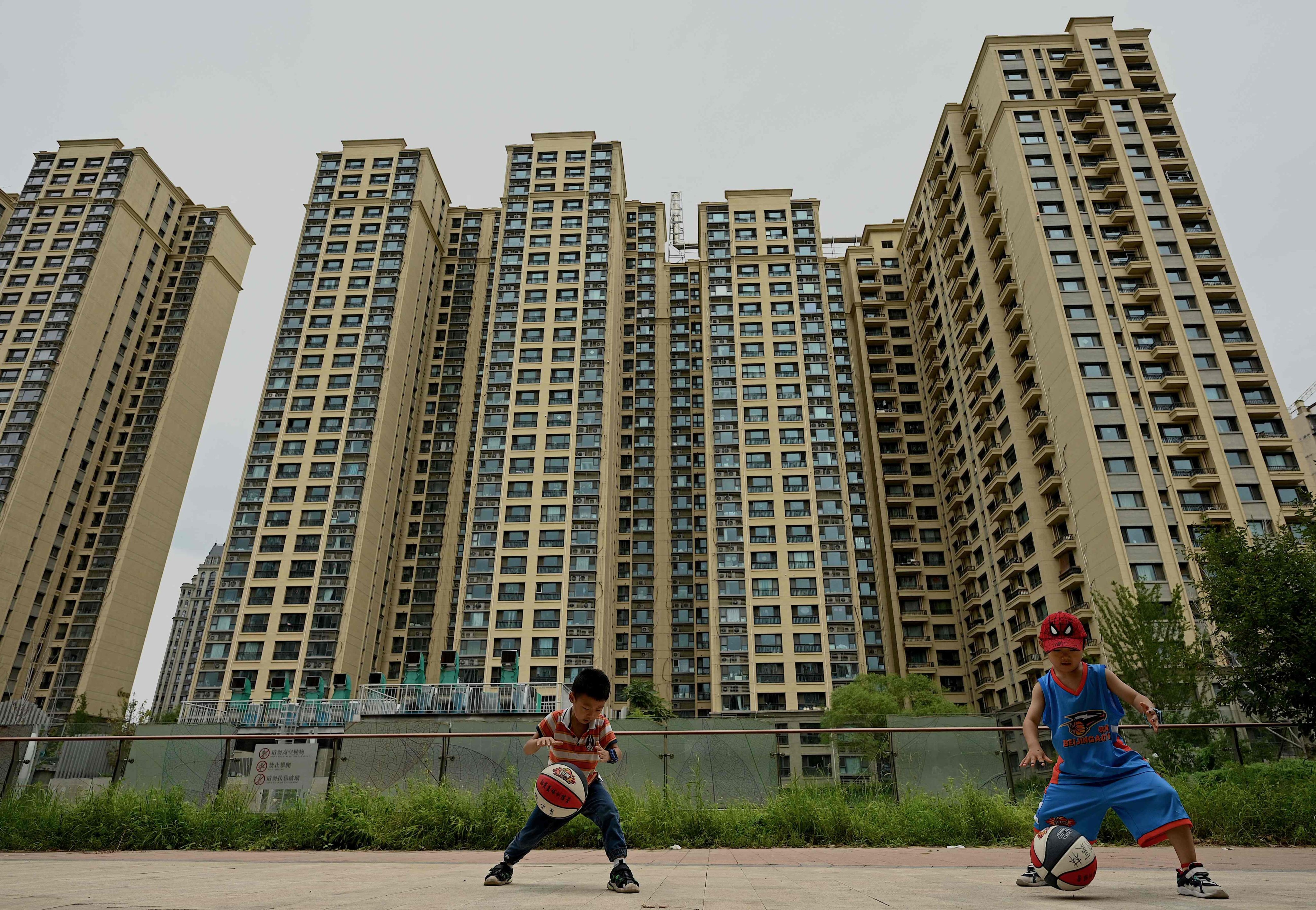 A July 28 picture shows children playing basketball in front of a housing complex developed by troubled China Evergrande in Beijing. Photo: AFP