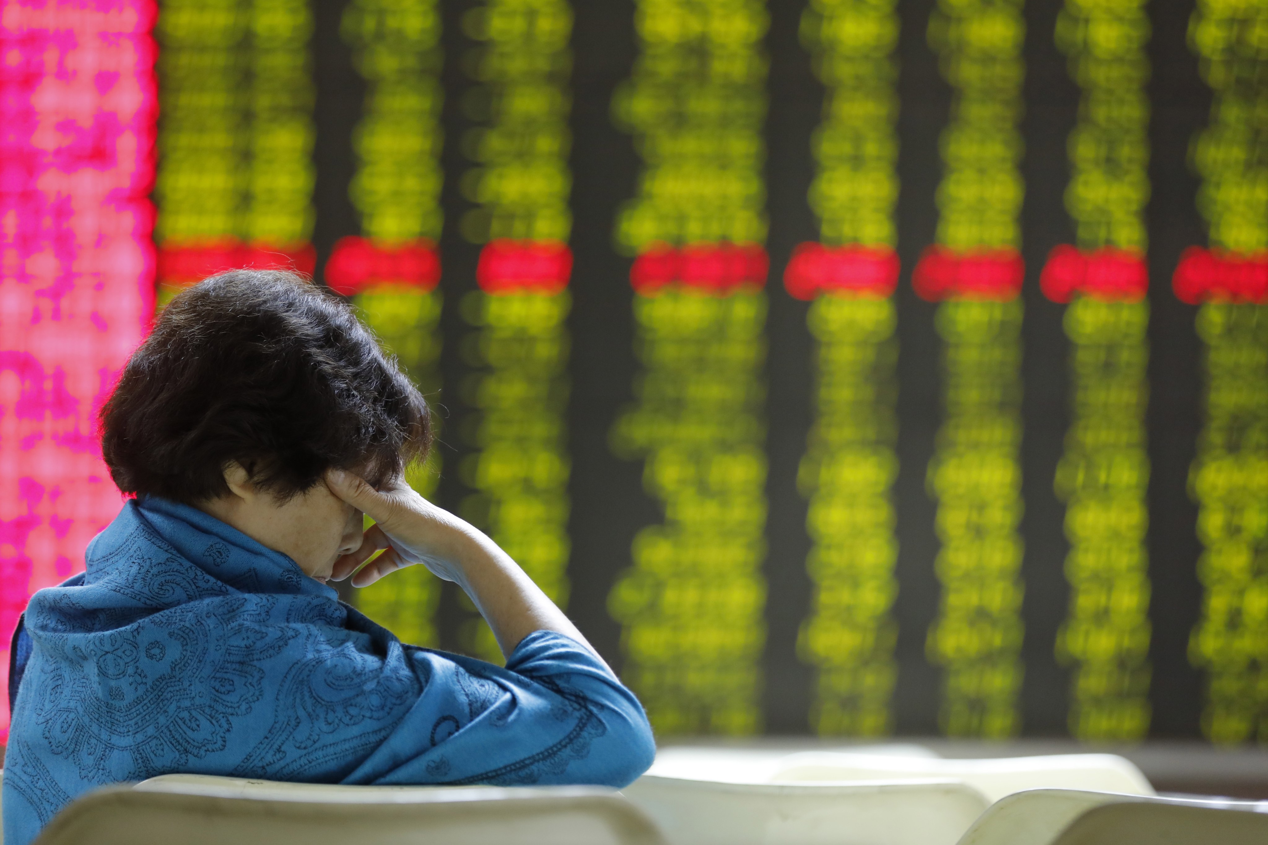 A Chinese investor in front of an electronic board showing stock prices at a securities brokerage house in Beijing. Photo: EPA-EFE