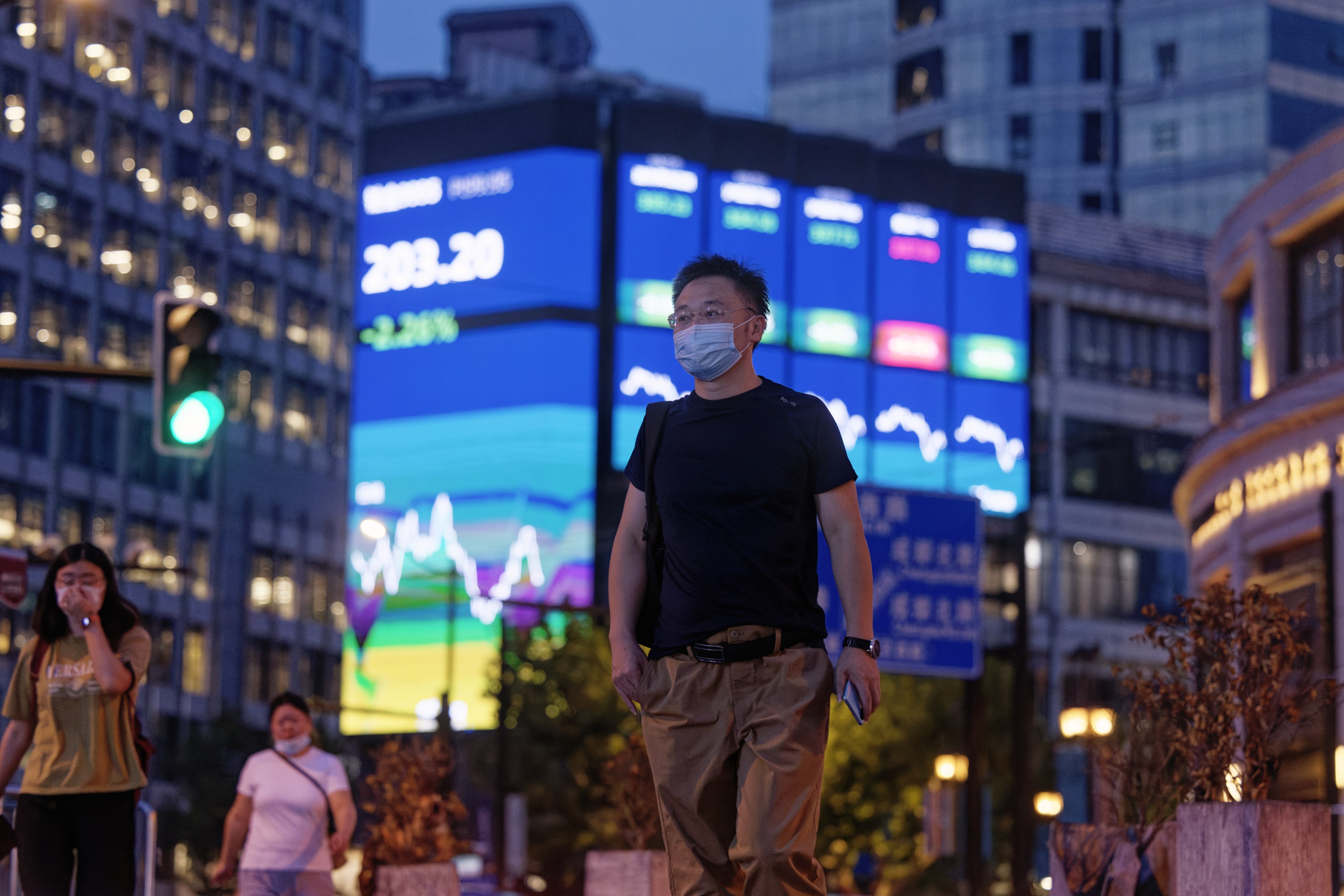 People walk in front of a screen showing stock exchange data in Shanghai. Traders are carefully weighing their moves amid China’s ongoing power crisis. Photo: EPA-EFE