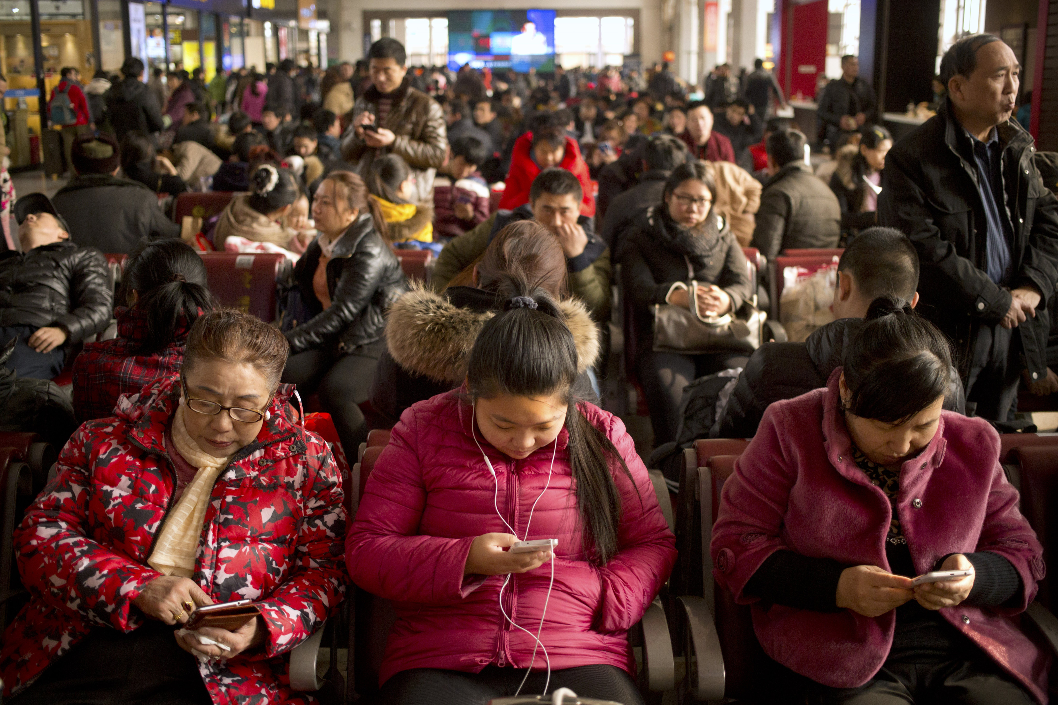 Passengers use their smartphones at the Beijing Railway Station, Jan. 30, 2016. By mid 2022, 99.6 per cent of Chinese netizens used a mobile phone. Photo: AP