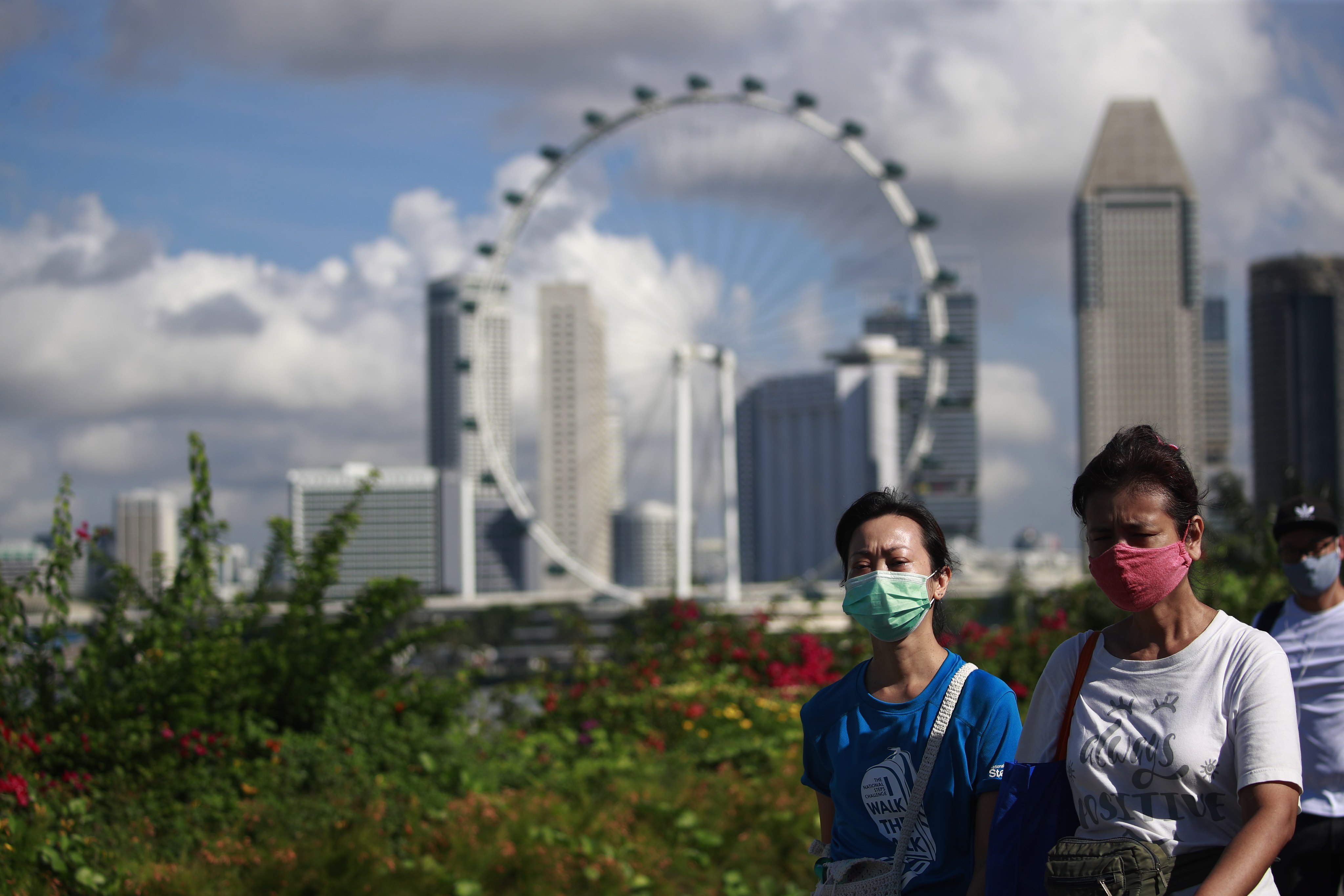 People walk with the Singapore Flyer in the background. Photo: EPA-EFE