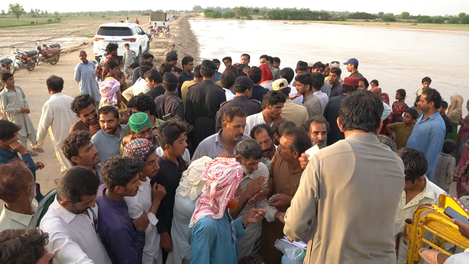 People displaced by floods in Pakistan swarm around a humanitarian worker distributing relief goods in Dera Ghazi Khan, Pakistan. Photo: Salman Farooque
