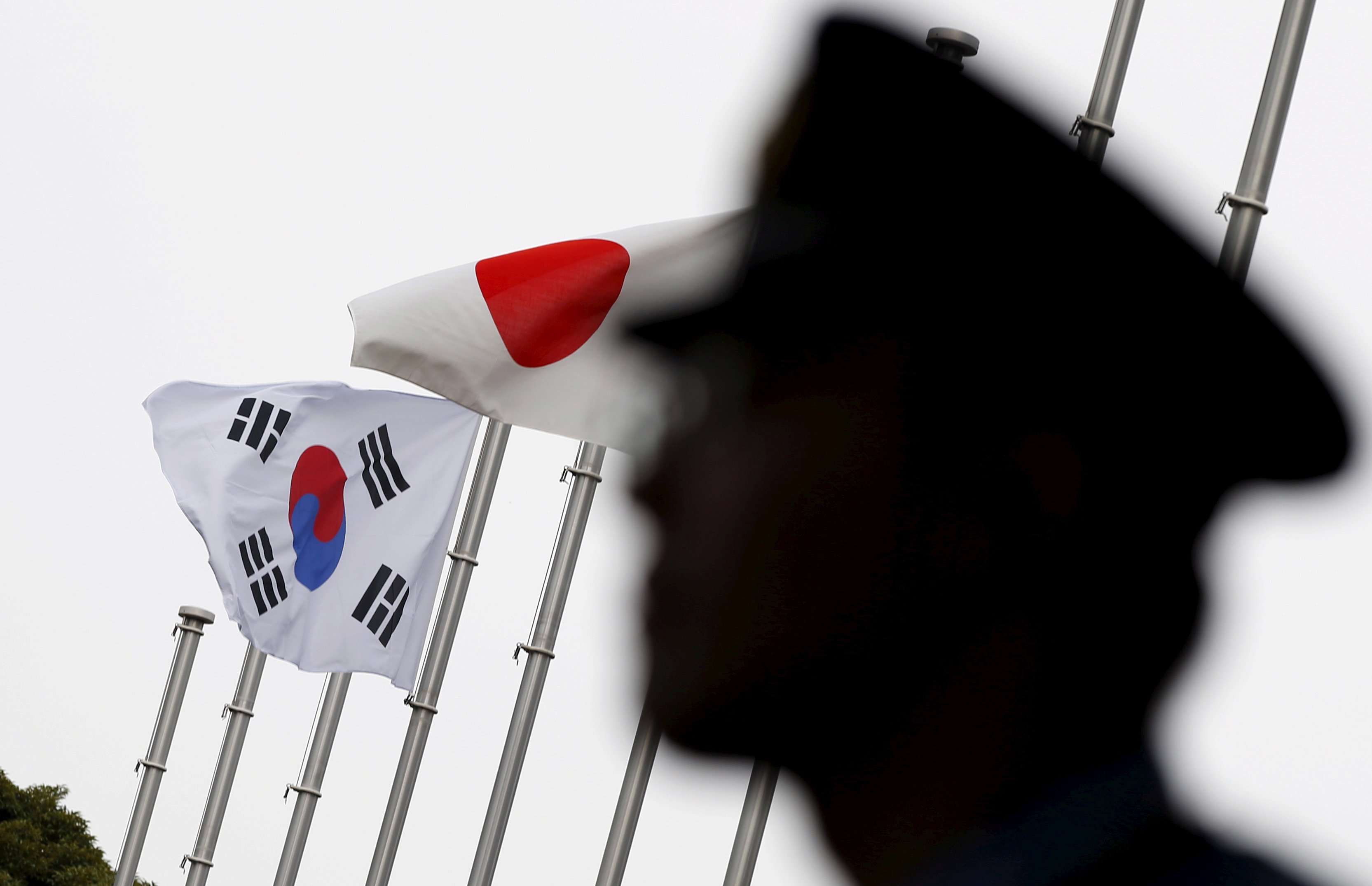 A police officer stands guard near Japan and South Korea national flags at hotel, where South Korean embassy in Japan is holding the reception to mark the 50th anniversary of normalisation of ties between Seoul and Tokyo, in Tokyo on June 22, 2015. Photo: Reuters/File