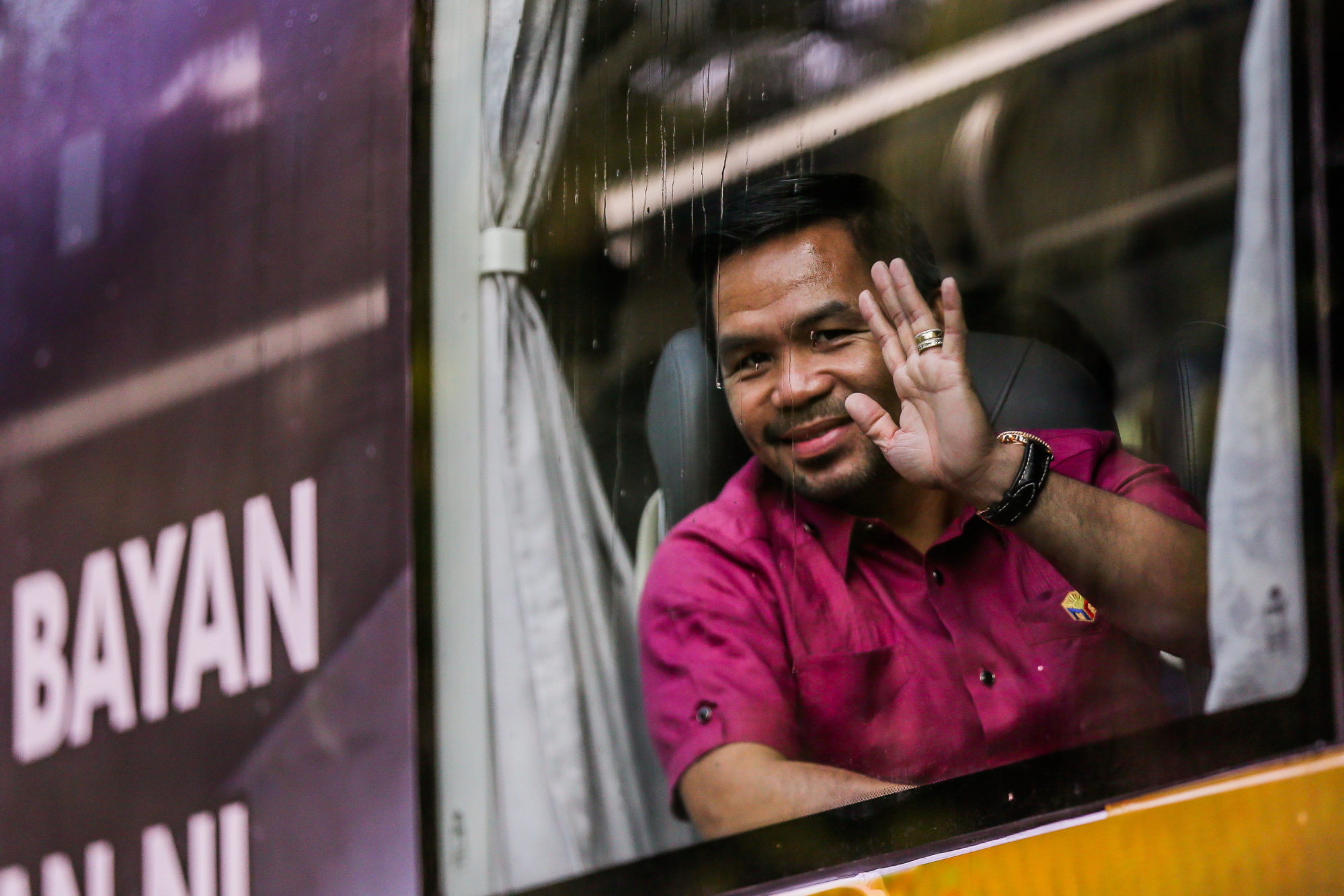 Manny Pacquiao waves inside a bus on his way to file his certificate of candidacy for president in Pasay City. Photo: Xinhua