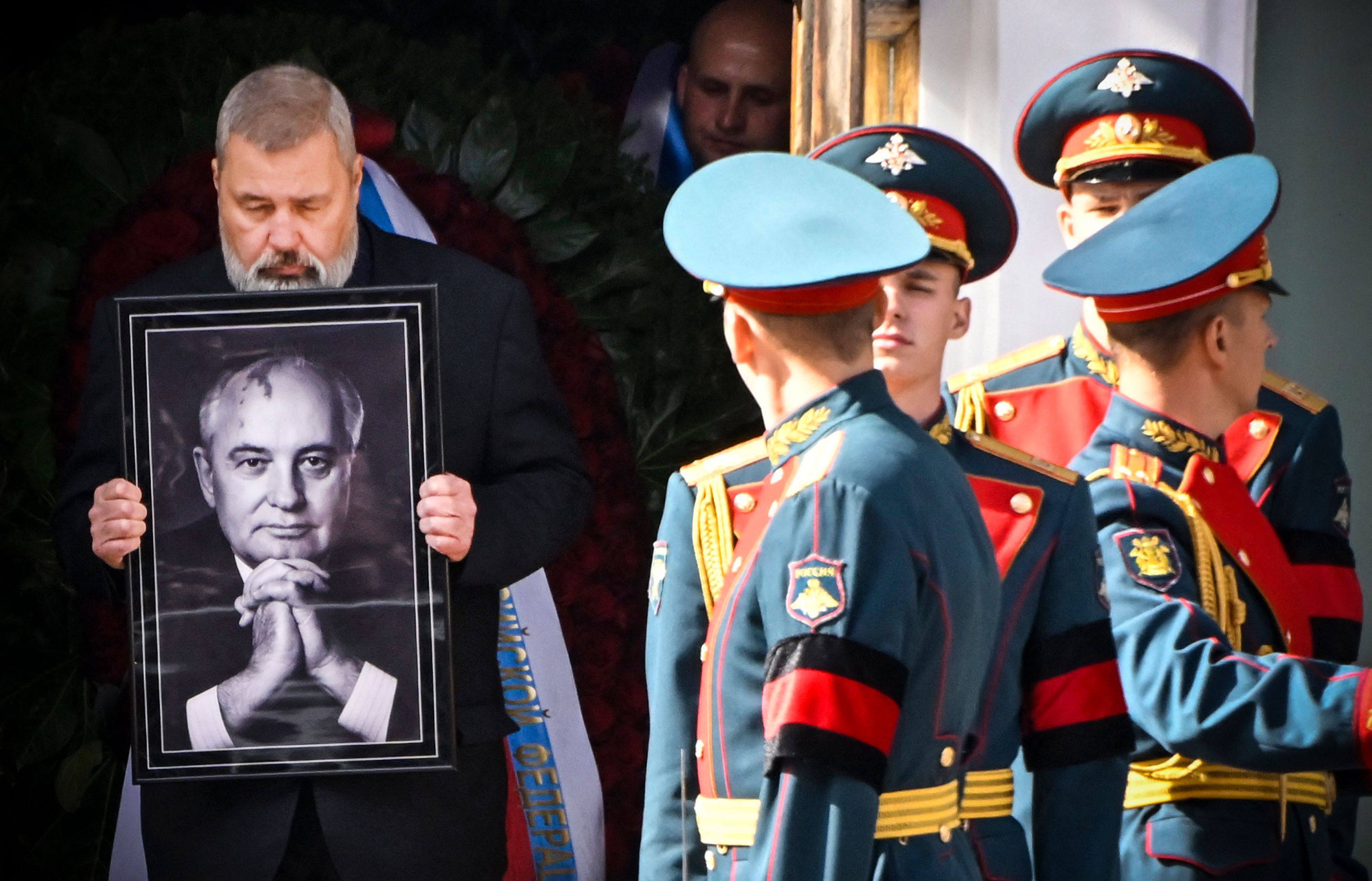 Honour guards stand by a man holding a photograph of the late Soviet leader Mikhail Gorbachev, as his coffin is brought out after a memorial service at the Pillar Hall of the House of the Unions on September 3. Russian President Vladimir Putin did not attend the funeral. Photo: AFP 