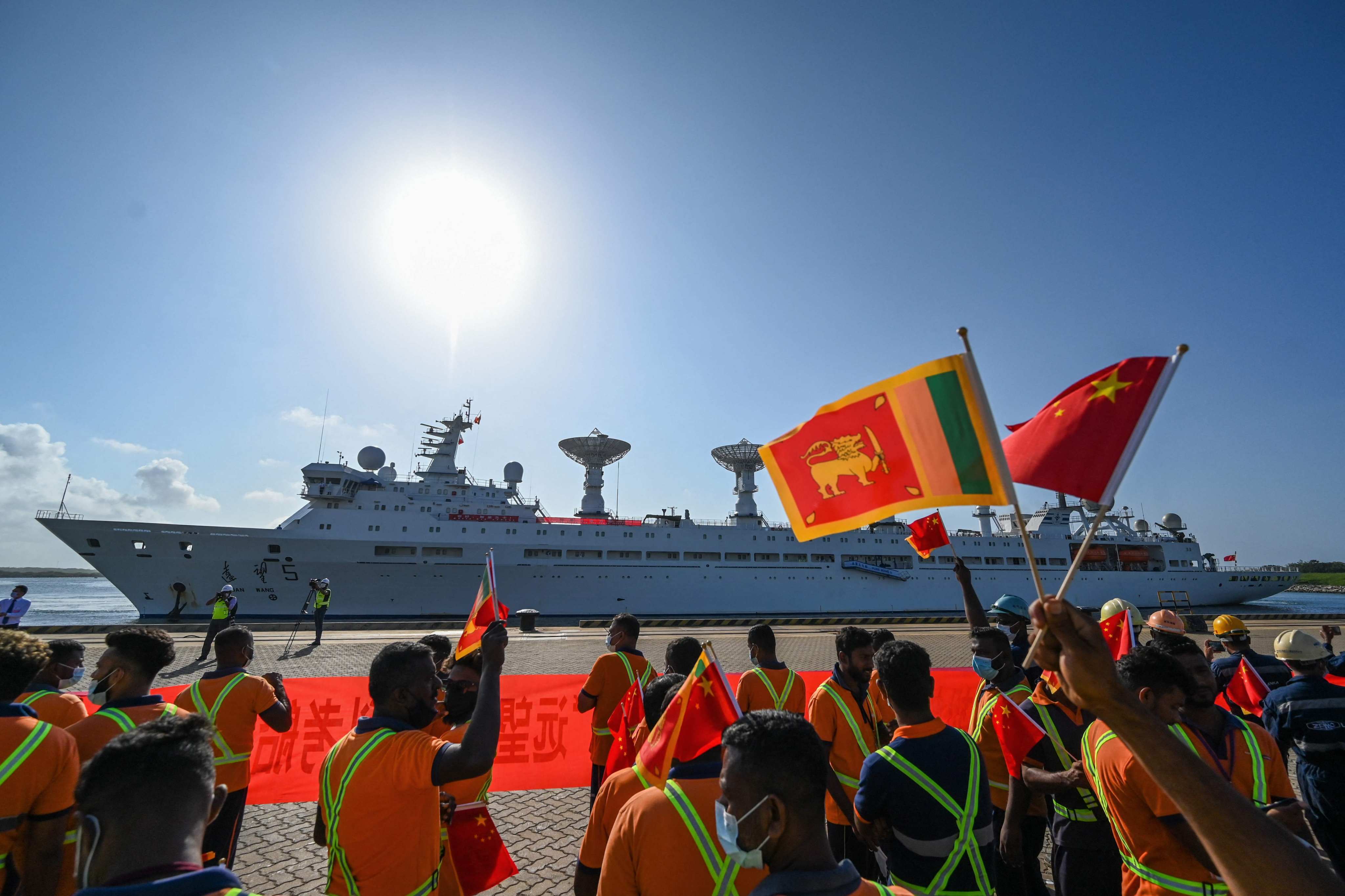 Workers wave China’s and Sri Lanka’s national flags to welcome a Chinese research and survey vessel to Hambantota port last month. Photo: AFP