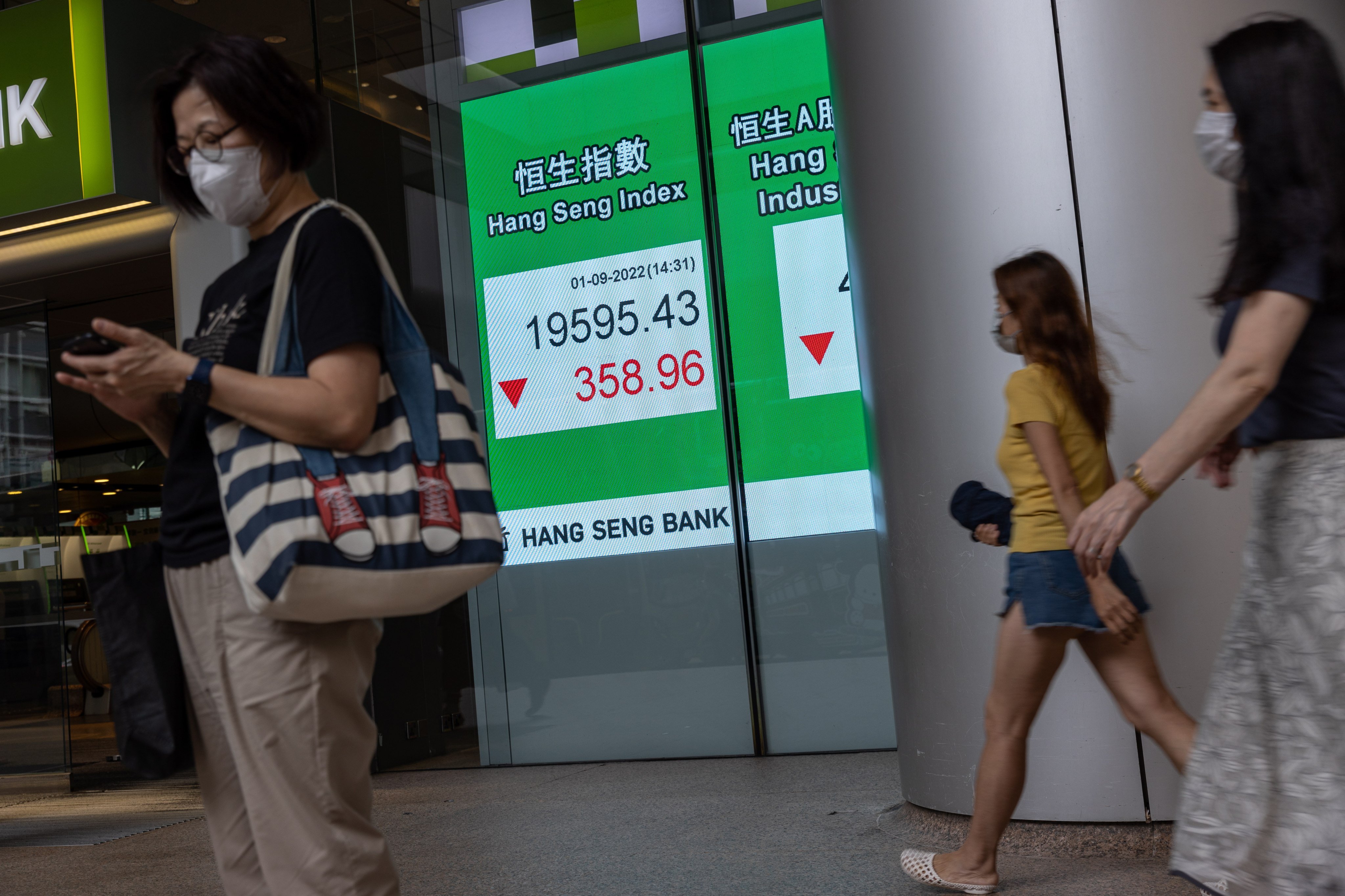 Pedestrians walk past a billboard showing the Hang Seng Index. The  benchmark has declined 19 per cent year to date. Photo: EPA-EFE