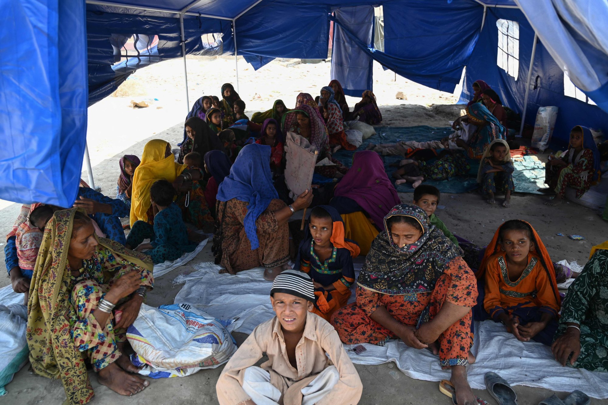 Displaced flood-affected people sit in a tent at a makeshift camp in Sukkur, Sindh province. Photo: AFP