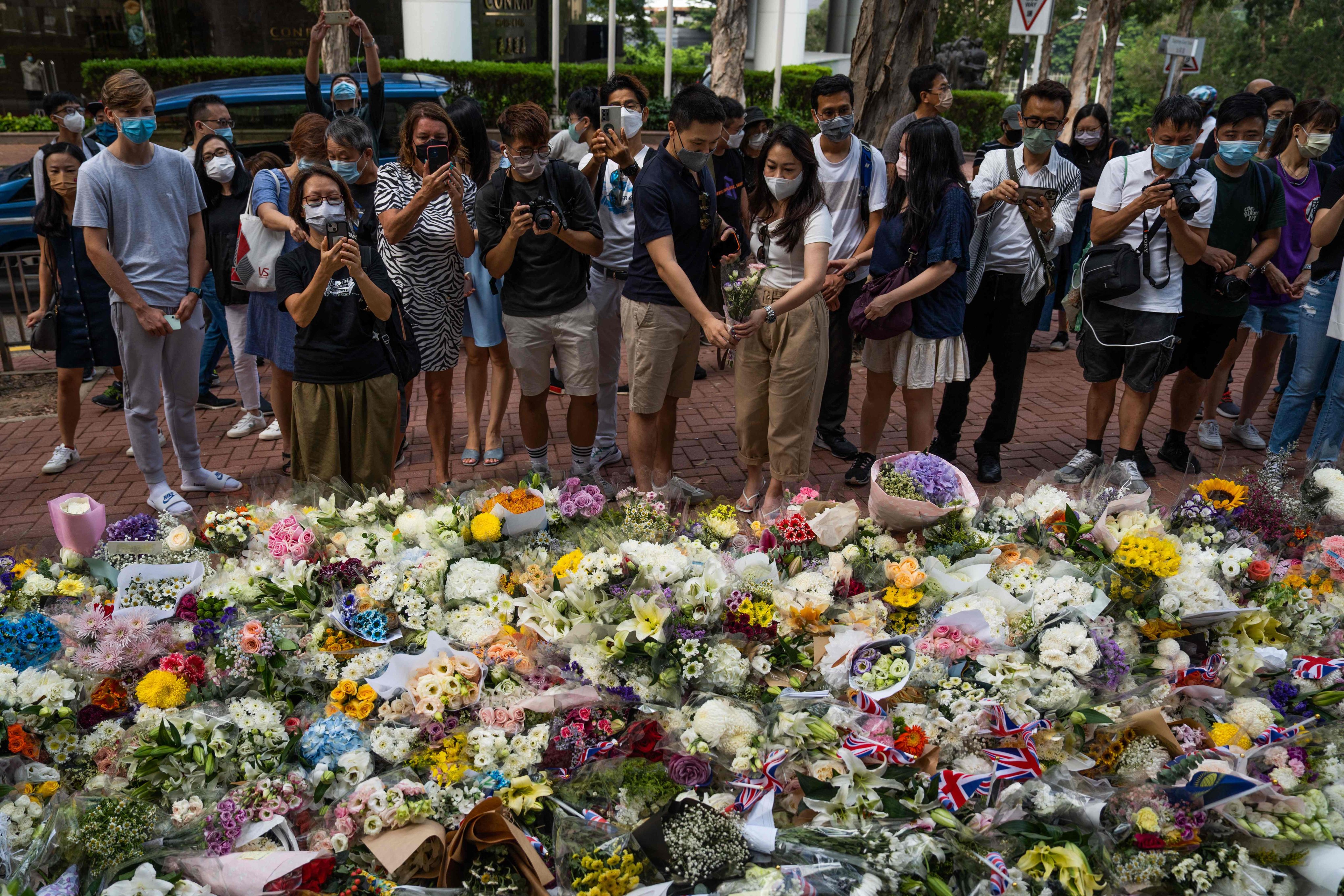 People gather next to flowers placed as a tribute for Queen Elizabeth outside the British Consulate in Hong Kong on September 10. Photo: AFP