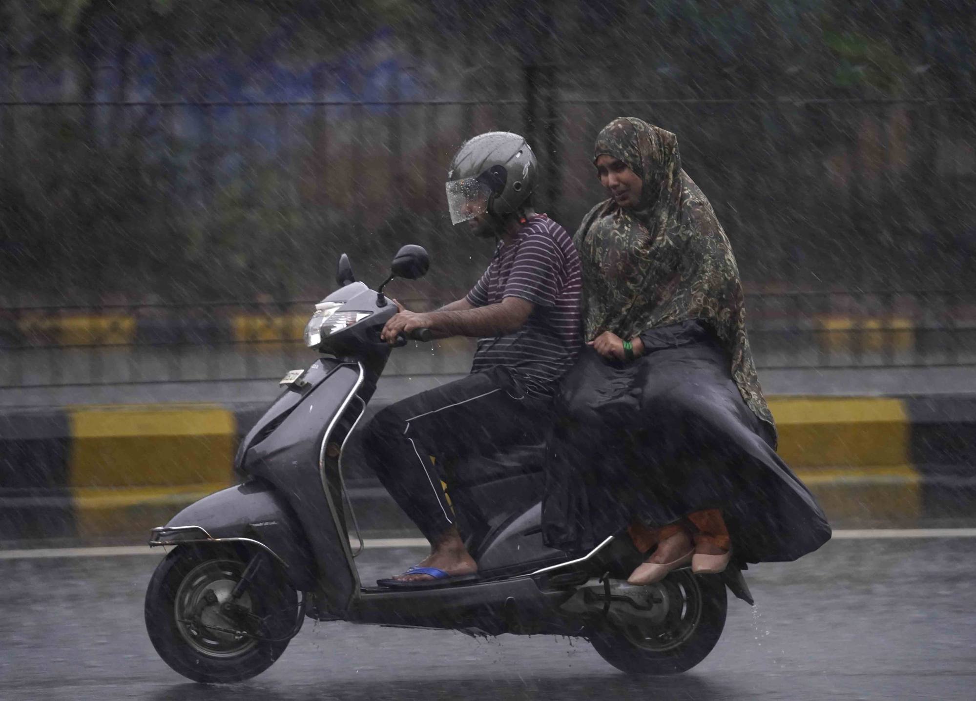 People ride a scooter in the rain in Hyderabad, India on September 7. India wants e-scooters and e-bikes to make up 80 per cent of total two-wheeler sales by 2030, from about 2 per cent now. Photo: AP
