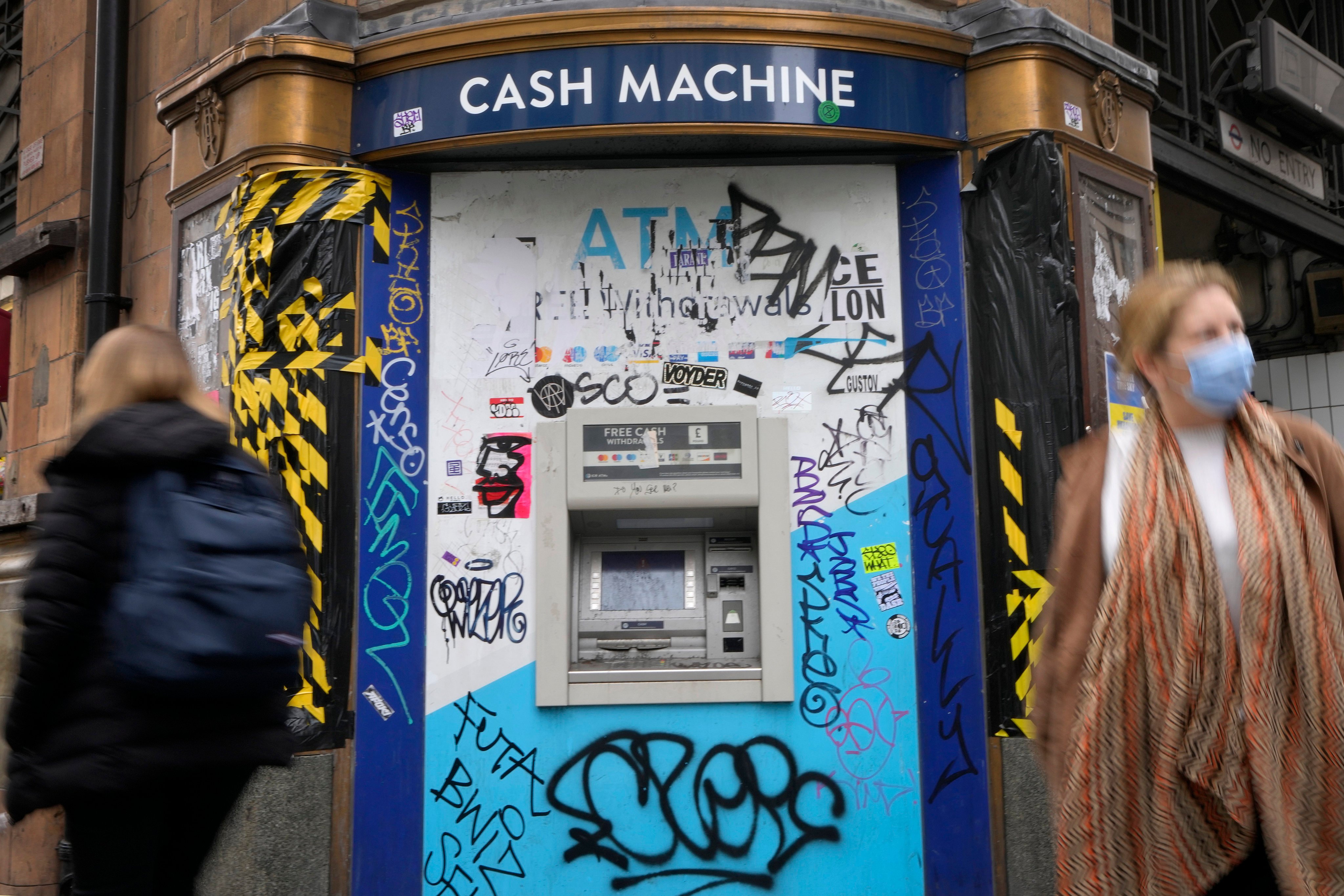 Shoppers pass a graffitied cash machine on Oxford Street in London. Britain’s Prime Minister Liz Truss inherits an ailing economy on the brink of a potentially long recession. Photo: AP 