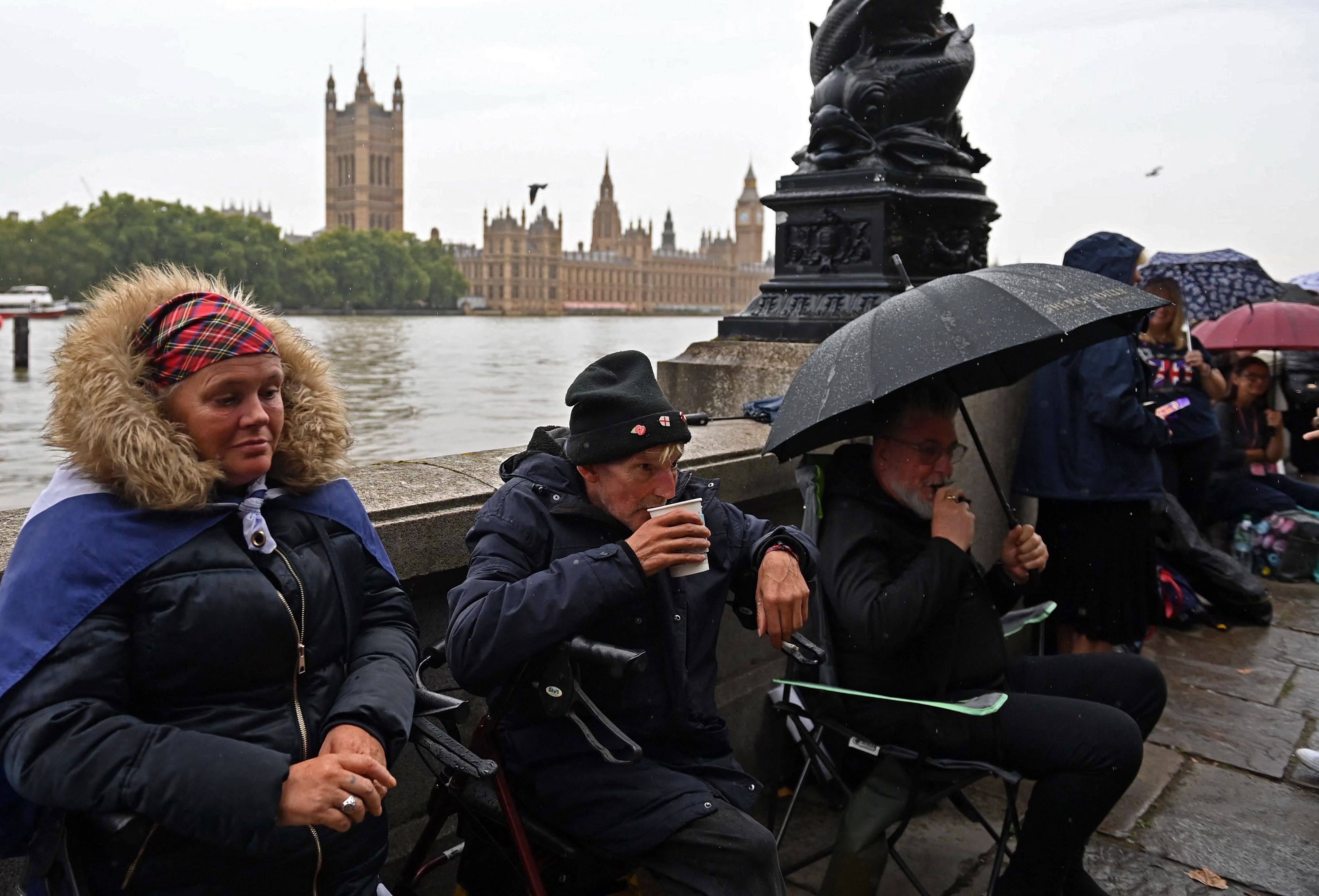People queue in the rain along the south bank of the River Thames, opposite the Palace of Westminster, home to Westminster Hall and the Houses of Parliament, in London on September 13, as they wait to pay their respects during Queen Elizabeth’s lying in state. Photo: AFP