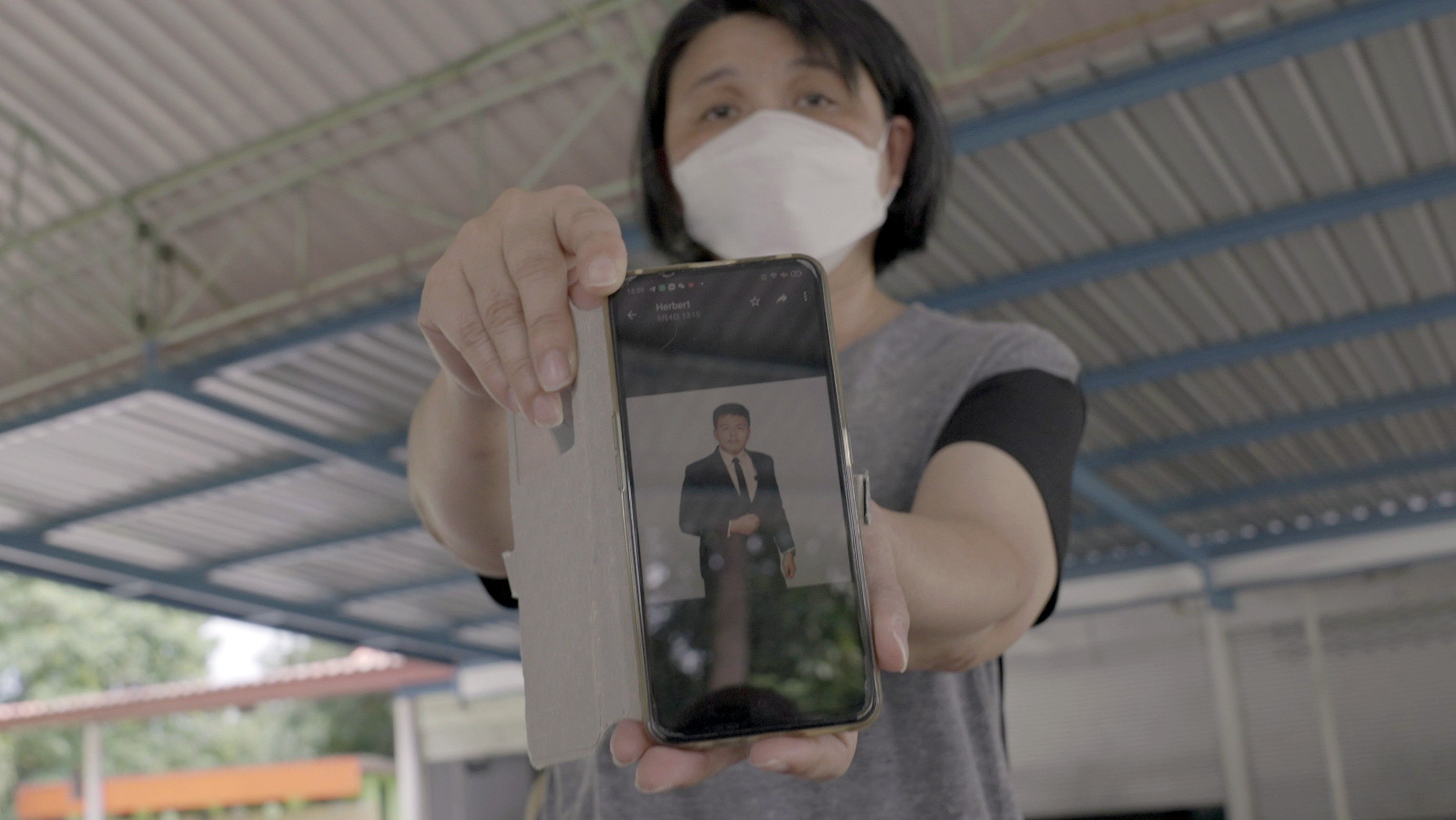 Malaysian Yang Fei Pin holds her phone showing a photograph of her late son Goi Zhen Feng. He died aged 23 in hospital in Thailand near the border with Myanmar, his death thought to be linked to scam gangs. Photo: Aidan Jones 