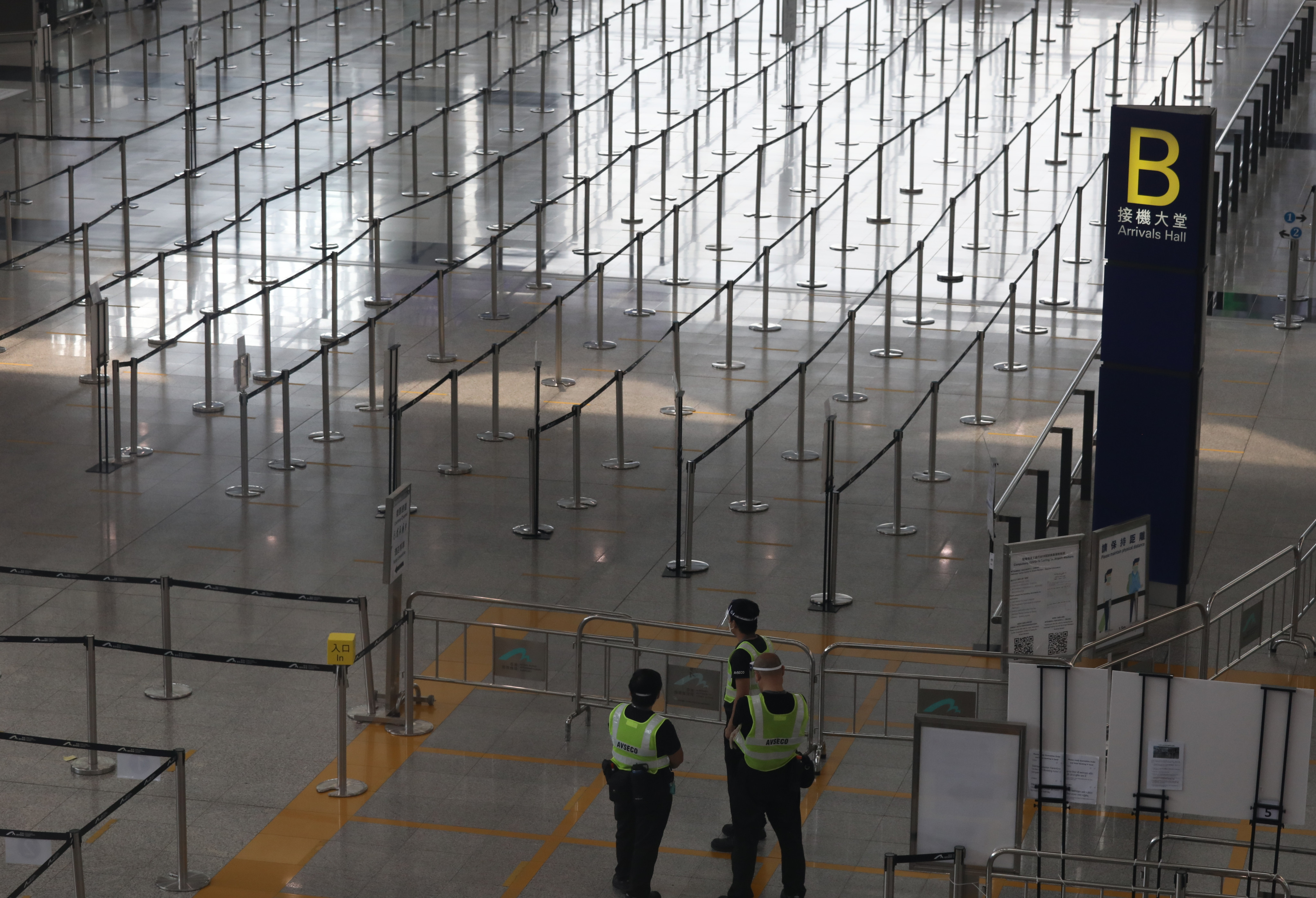 Security guards chat in an empty arrivals hall at Hong Kong International Airport on September 10. Despite sustained calls to fully reopen Hong Kong’s borders, pandemic restrictions remain in place and continue to weigh on the city’s attractiveness, competitiveness and economy. Photo: Yik Yeung-man