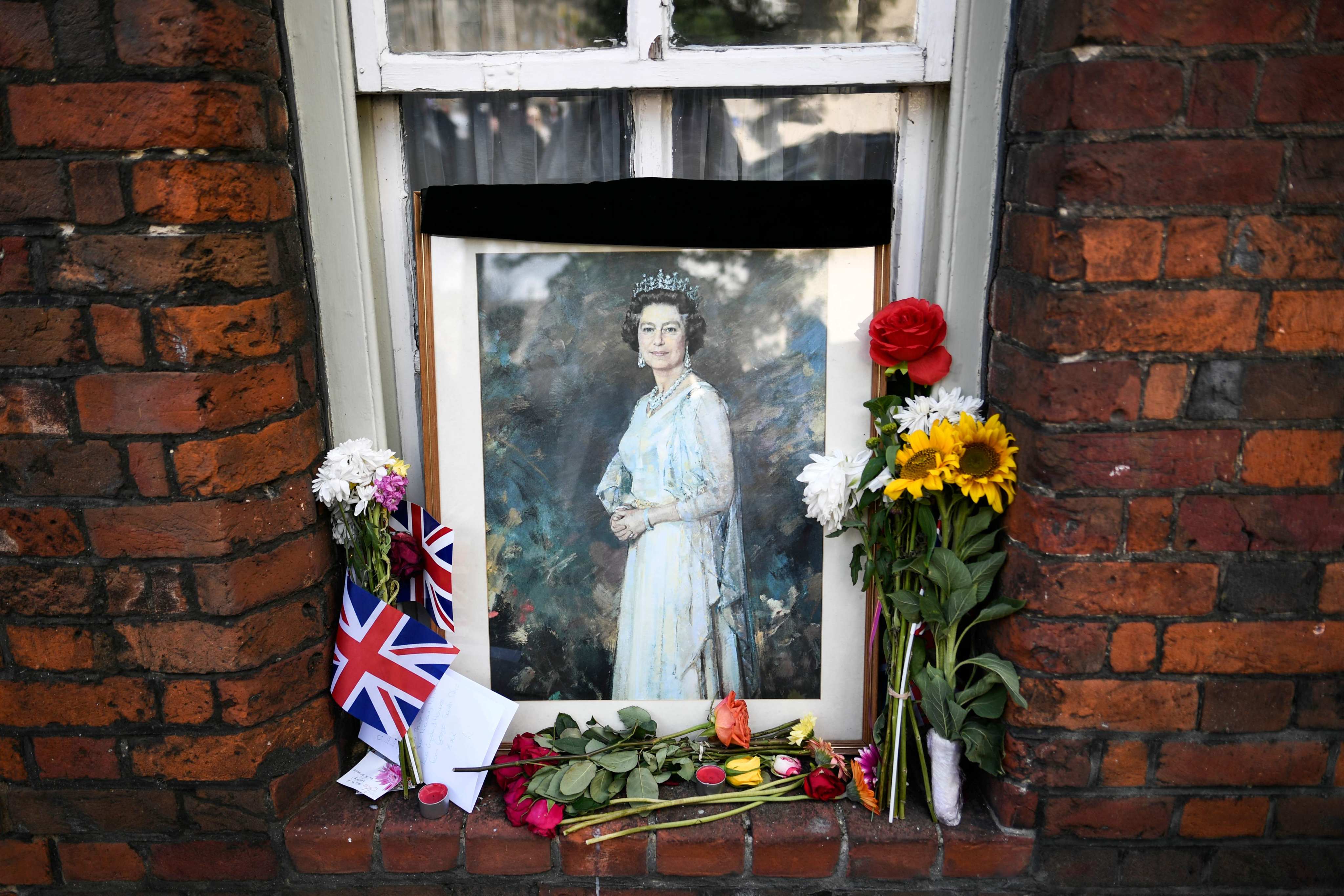 A picture of Britain’s Queen Elizabeth and floral tributes displayed in a window in Windsor. Photo: AFP