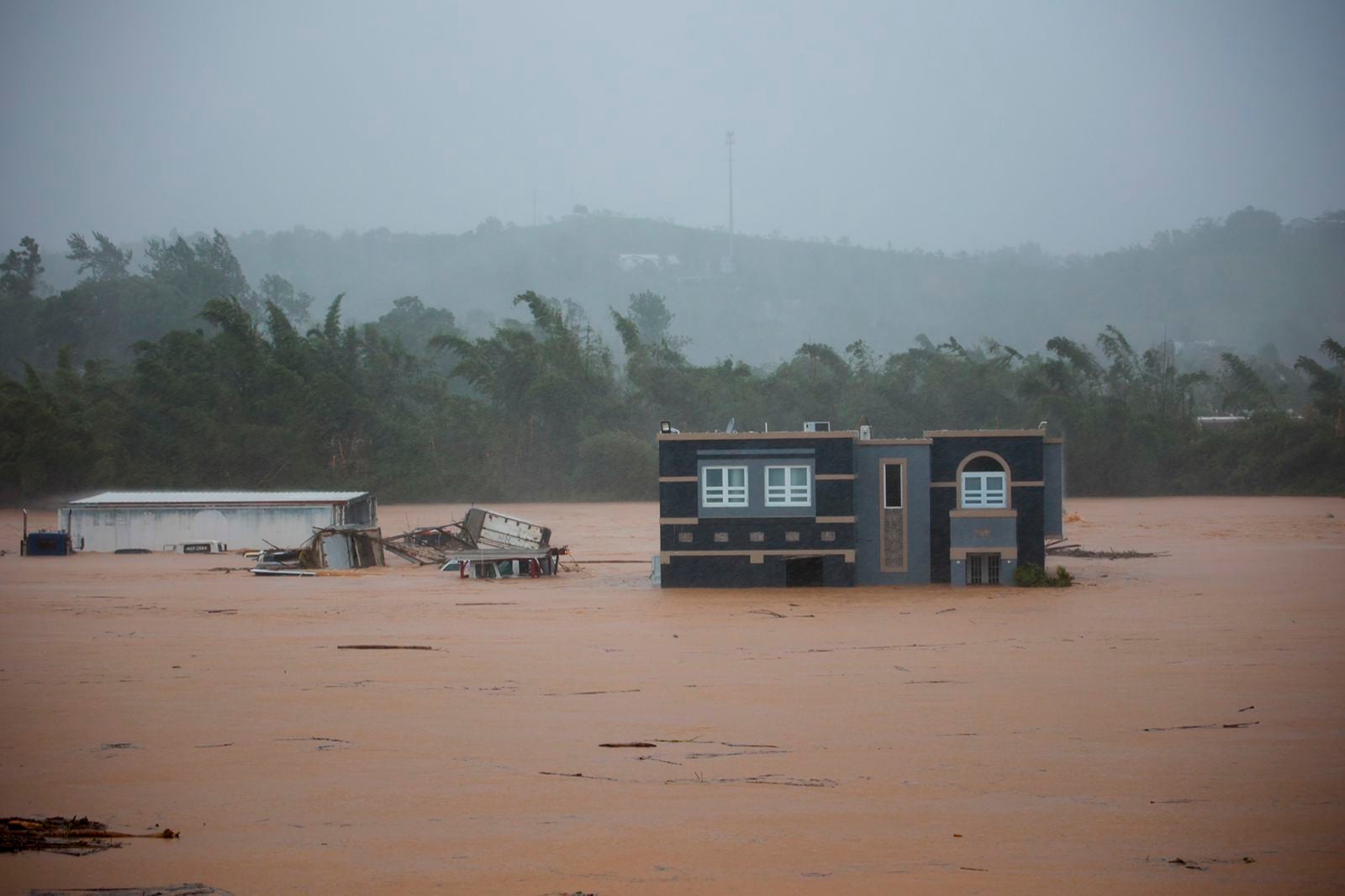 Three people inside a house await rescue from the floods caused by Hurricane Fiona in Cayey, Puerto Rico. Photo: AP