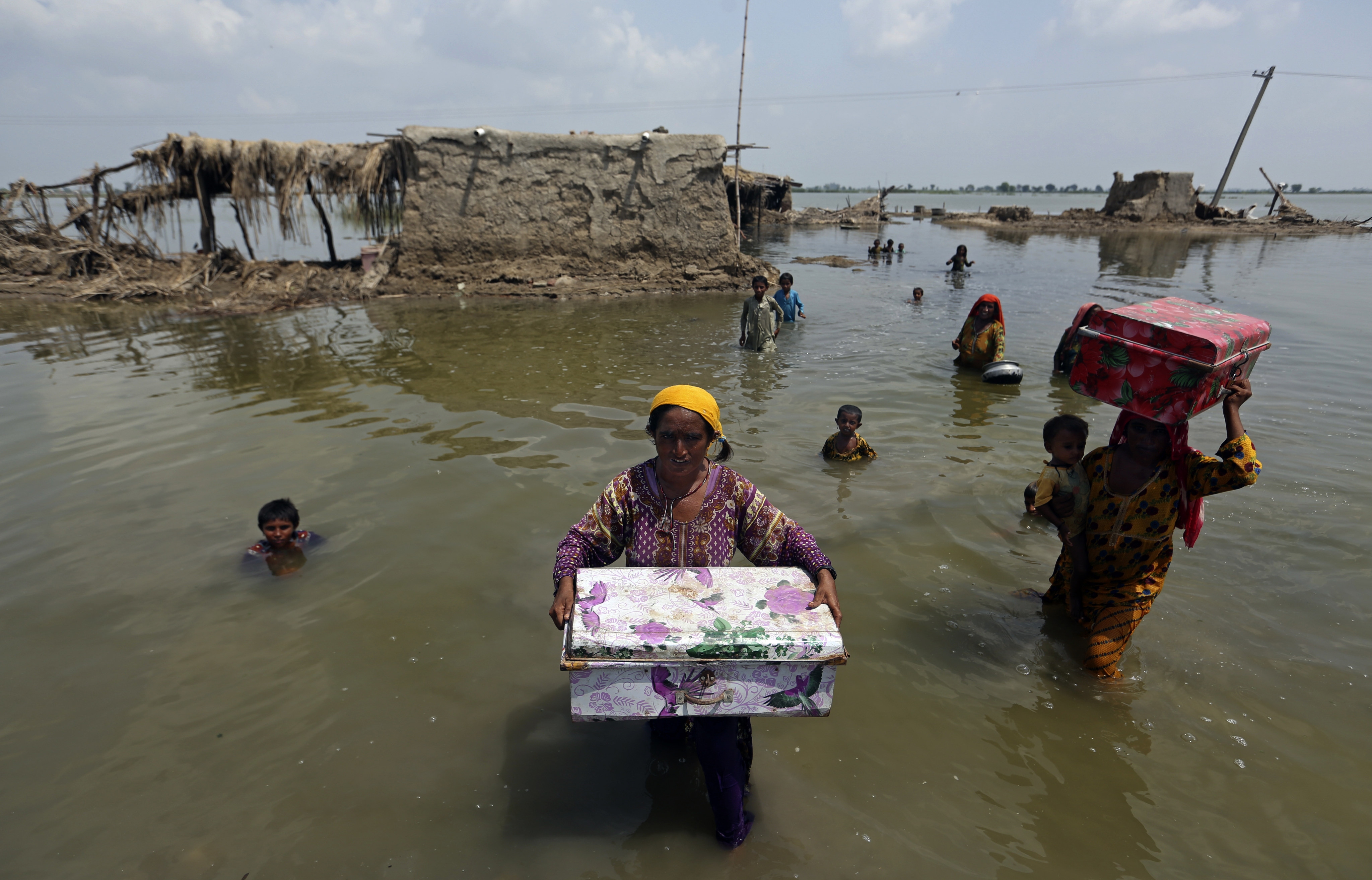 Women carry belongings salvaged from their flooded home after monsoon rains in the Qambar Shahdadkot district of Sindh province in Pakistan on September 6. Photo: AP
