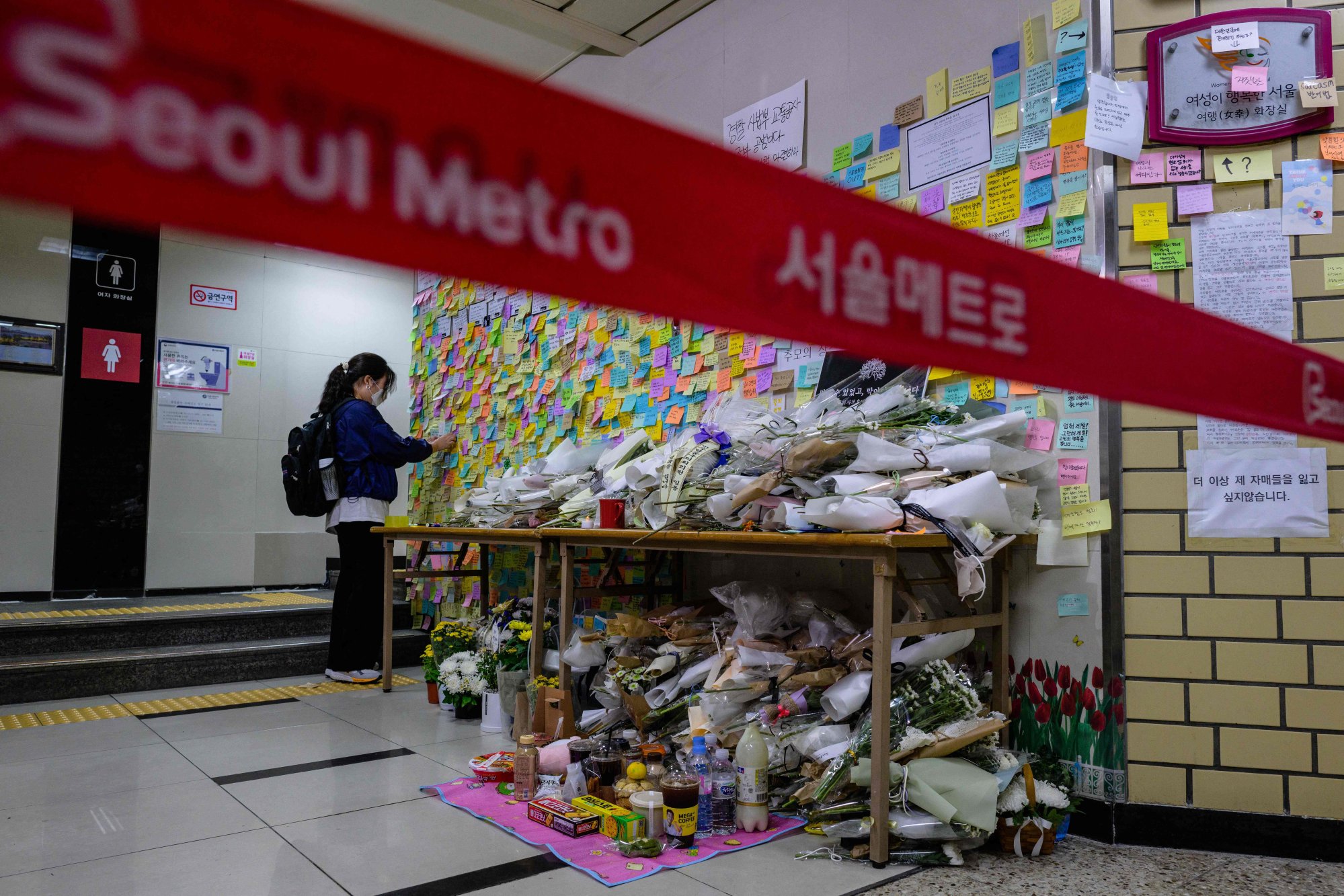 A woman pays her respects as she displays a note near the entrance to the women’s public toilet (back) at Sindang station in Seoul on September 19, 2022. Photo: AFP