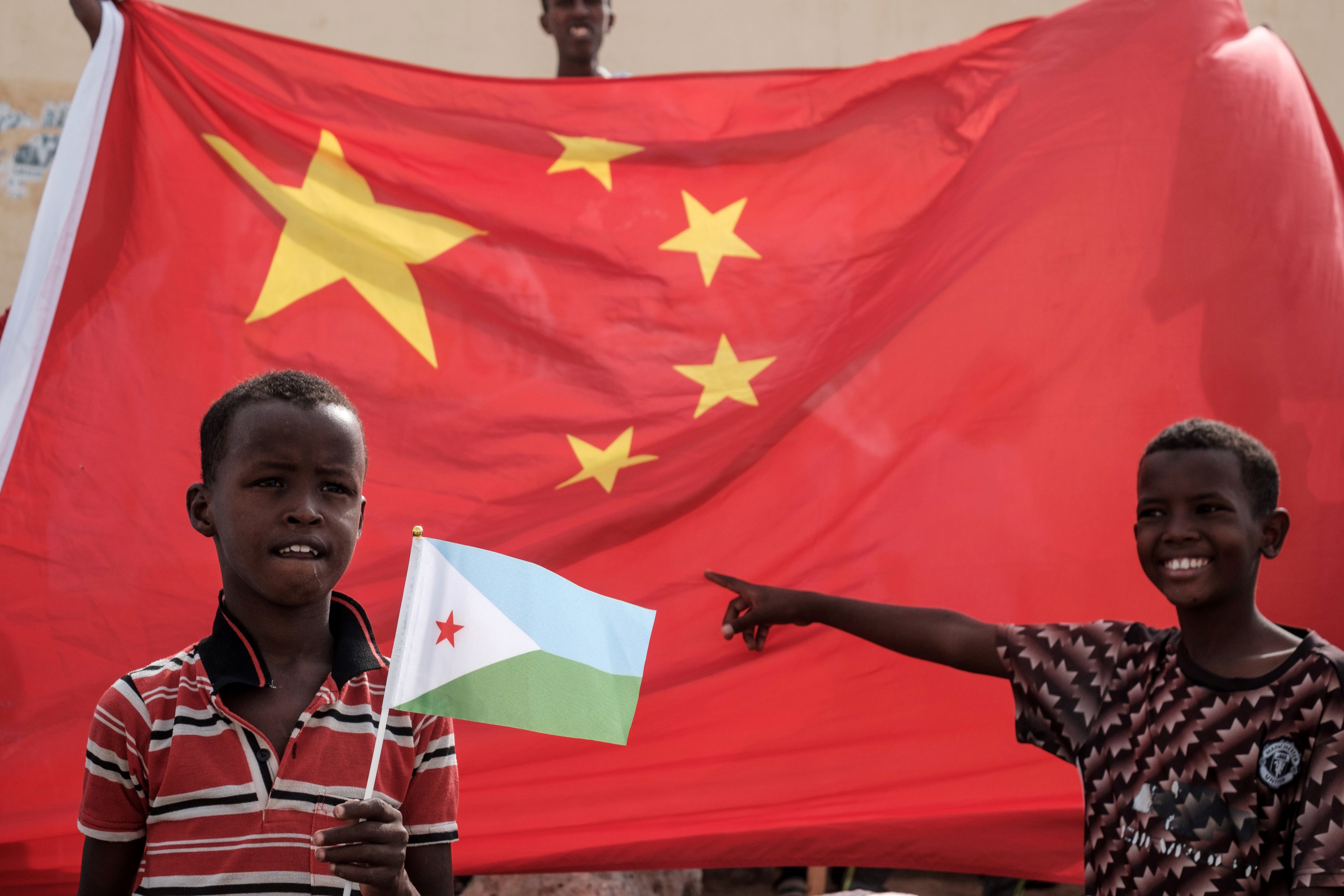 A boy holds Djibouti’s national flag in front of China’s national flag at the launch of a housing construction project in Djibouti in July 2018. Photo: AFP