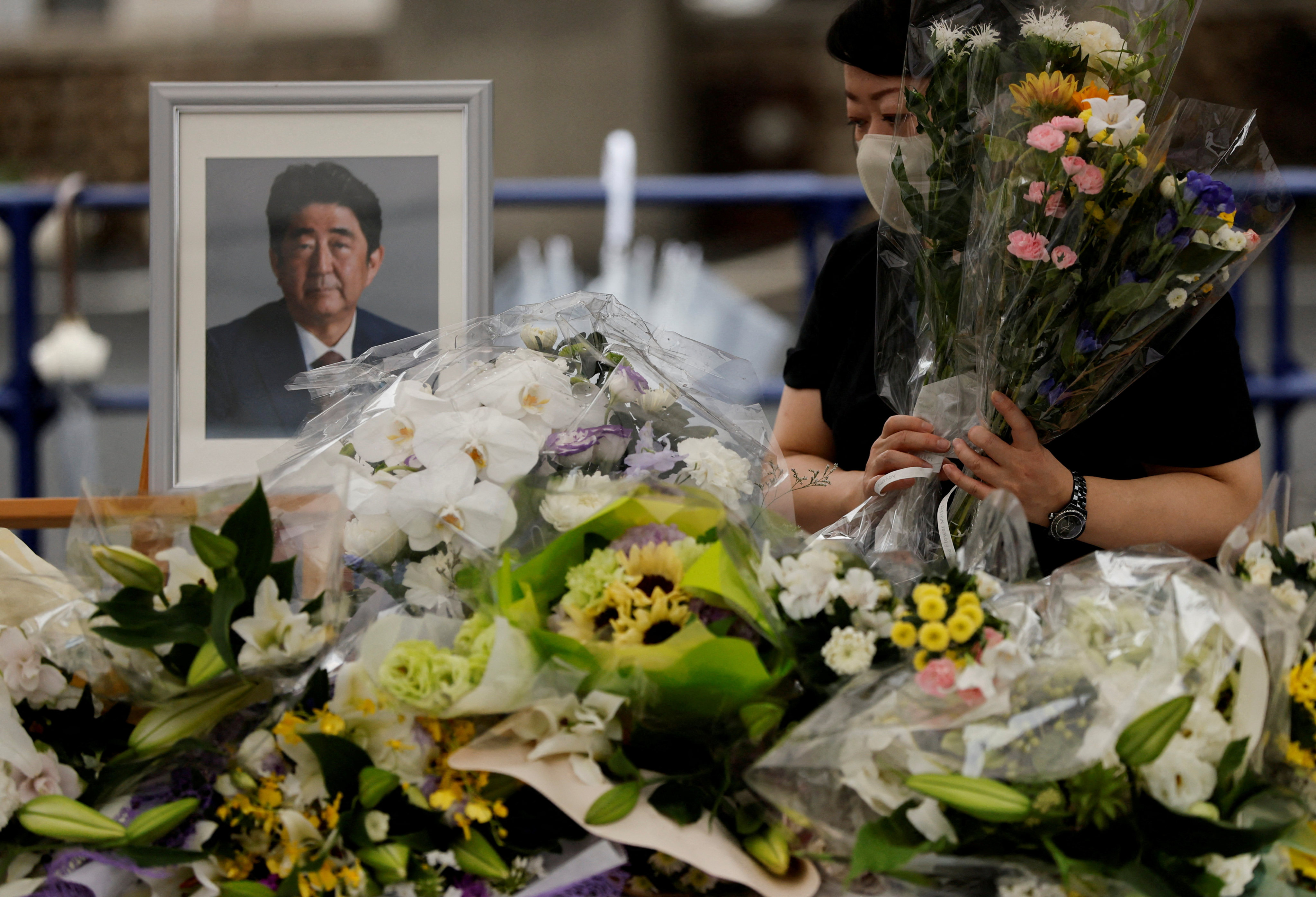 A mourner offers flowers next to a picture of late former Japanese Prime Minister Shinzo Abe, who was shot while campaigning for a parliamentary election, on the day to mark a week after his assassination at the Liberal Democratic Party headquarters, in Tokyo on July 15. Photo: Reuters