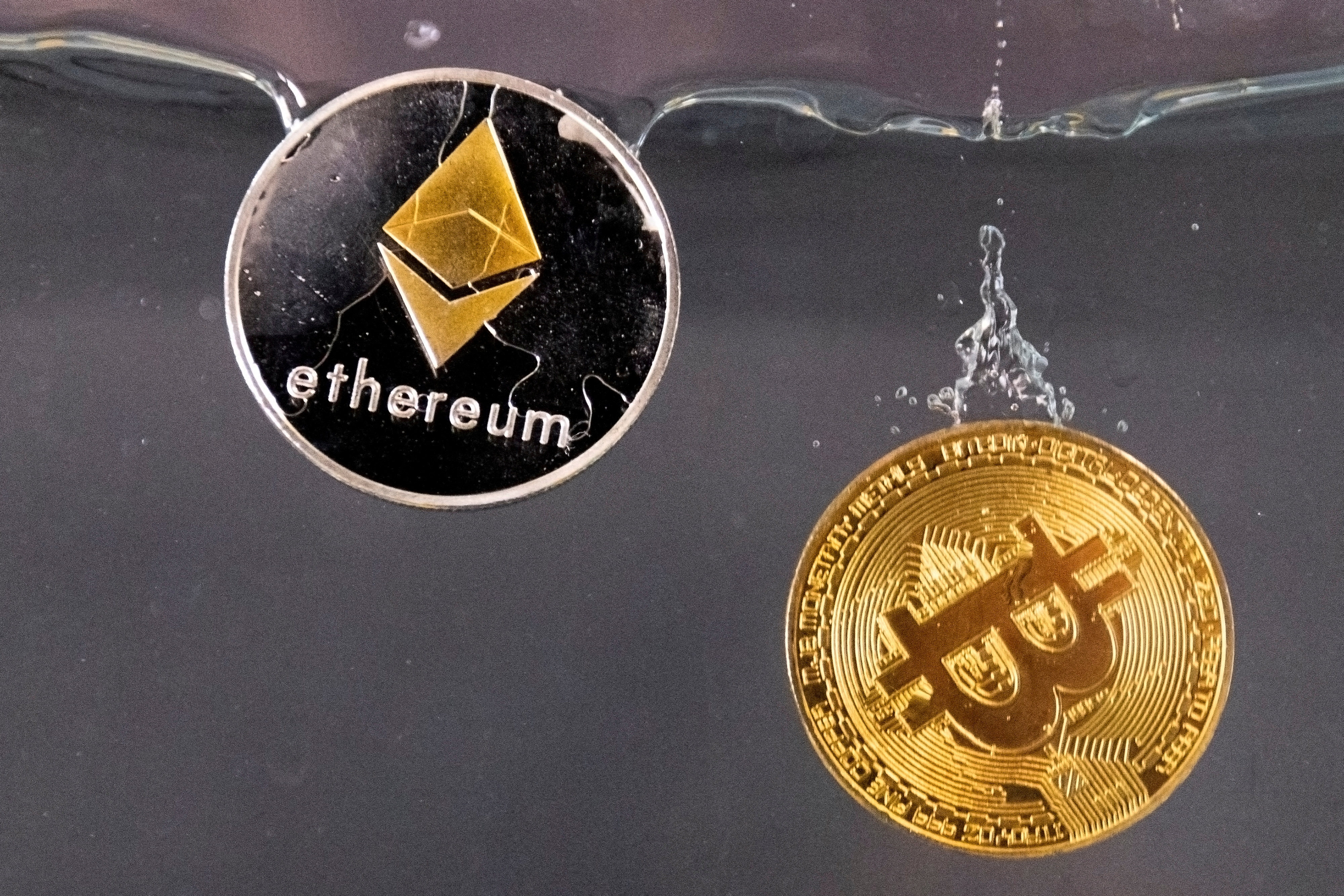 Souvenir tokens representing cryptocurrency bitcoin and ether plunge into water in this illustration taken May 17, 2022. Photo: Reuters