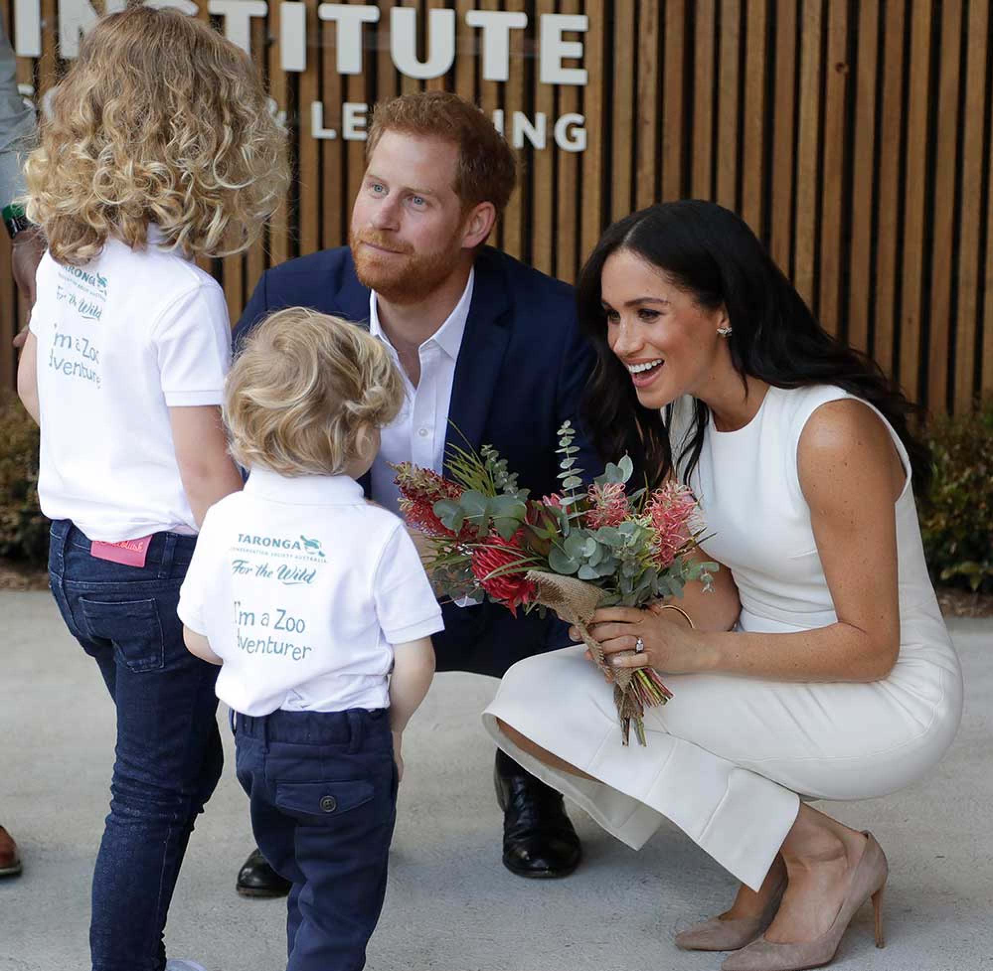 Prince Harry and Meghan Markle, Duchess of Sussex, receive native flowers from Finley Blue and Dasha Gallagher, left, at Taronga Zoo in Sydney, Australia, in October 2018. Photo: AP