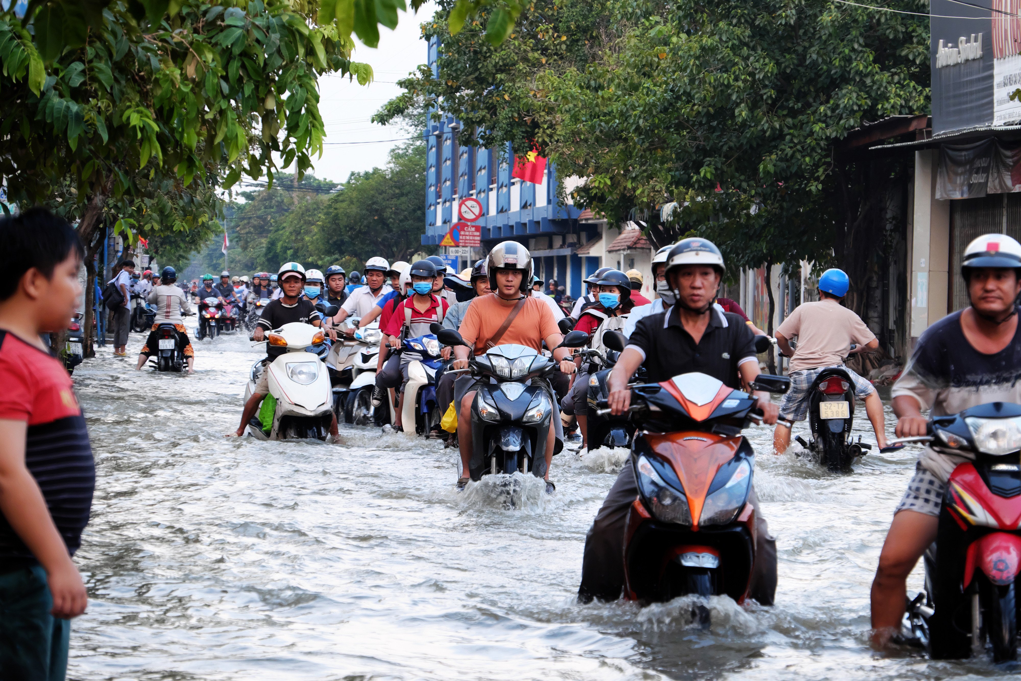 People ride mopeds and motorcycles through a flooded street in Ho Chi Minh City. Photo: Shutterstock