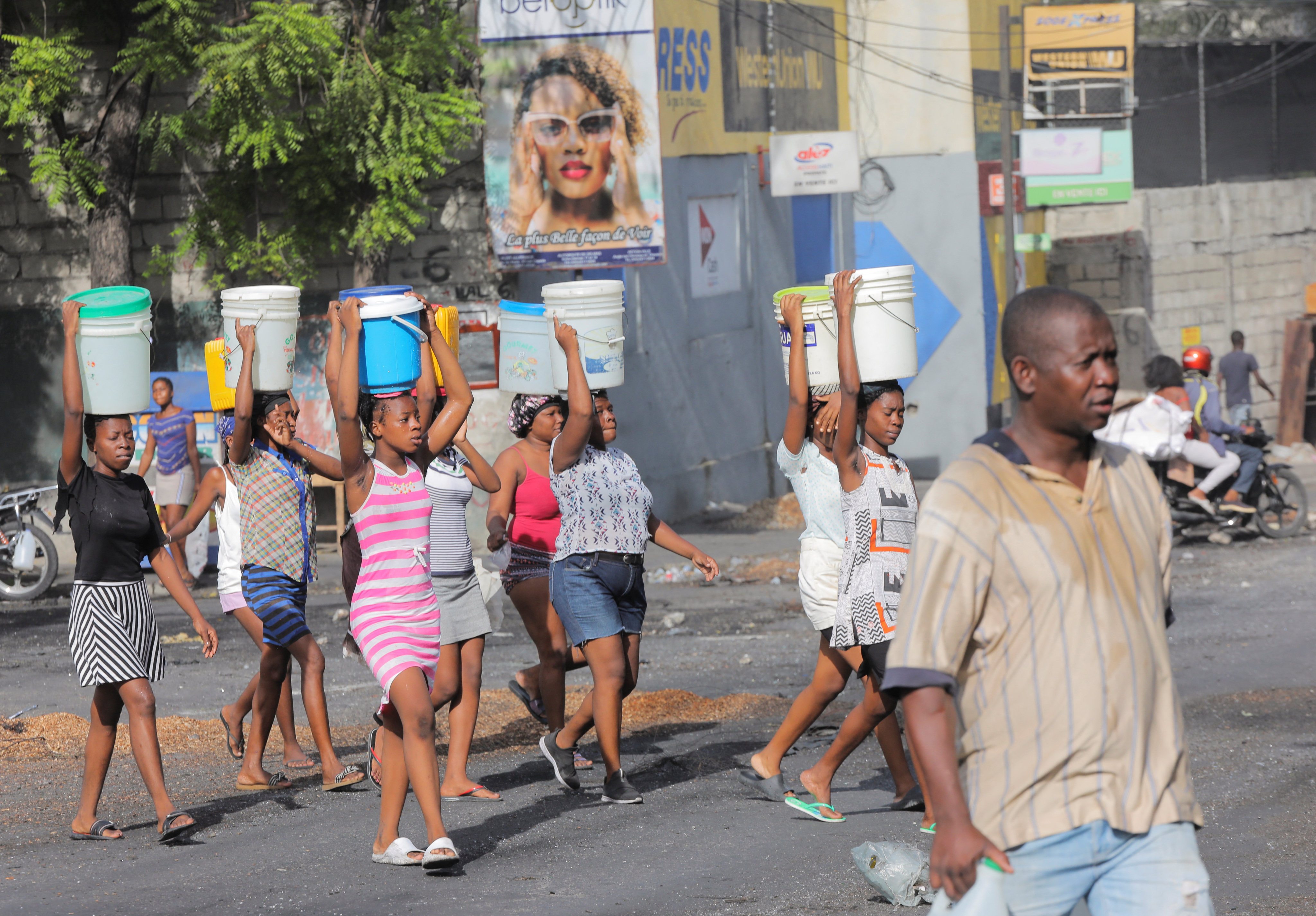 Women carry buckets filled with water amid shortages of water, cooking gas and other items in Port-au-Prince, Haiti. Photo: Reuters