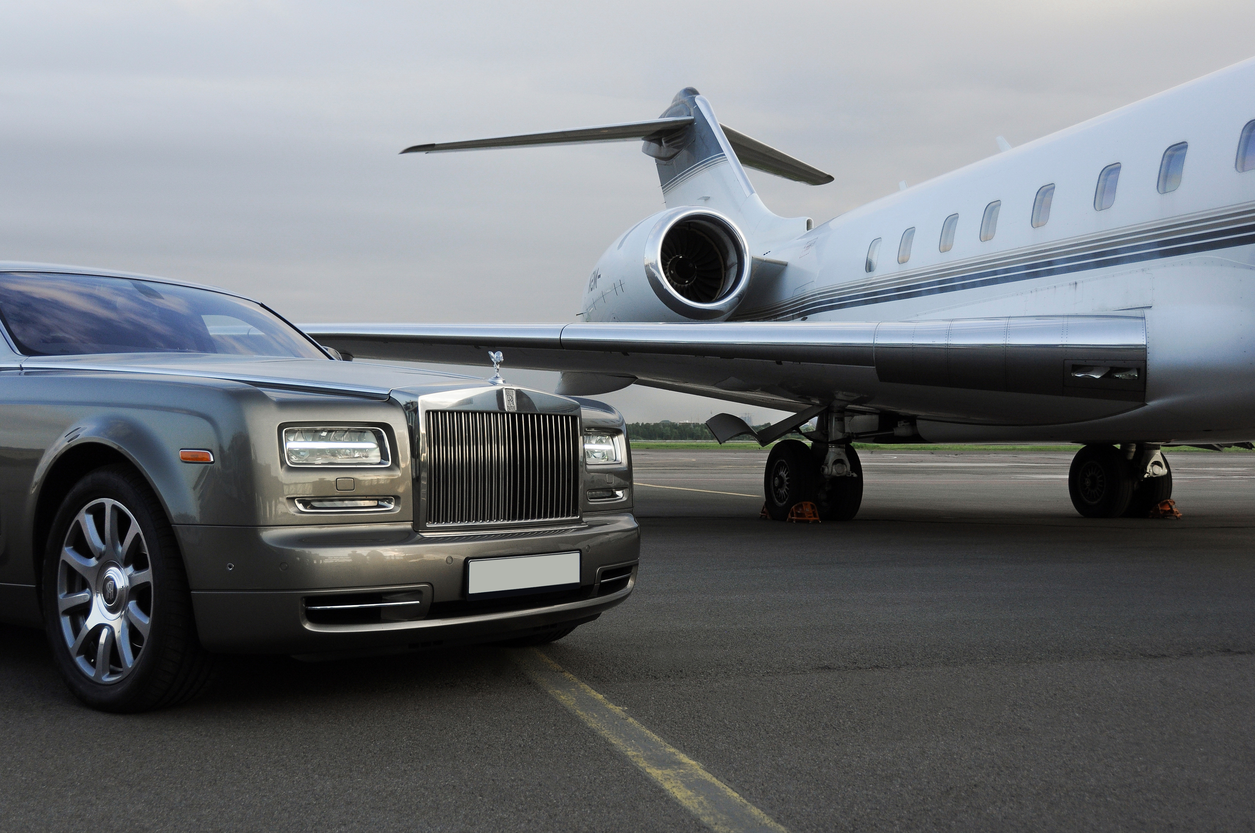 Private executive airplane with limousine Rolls Royce Phantom luxury car shown together at an airport runway. Photo: Shutterstock