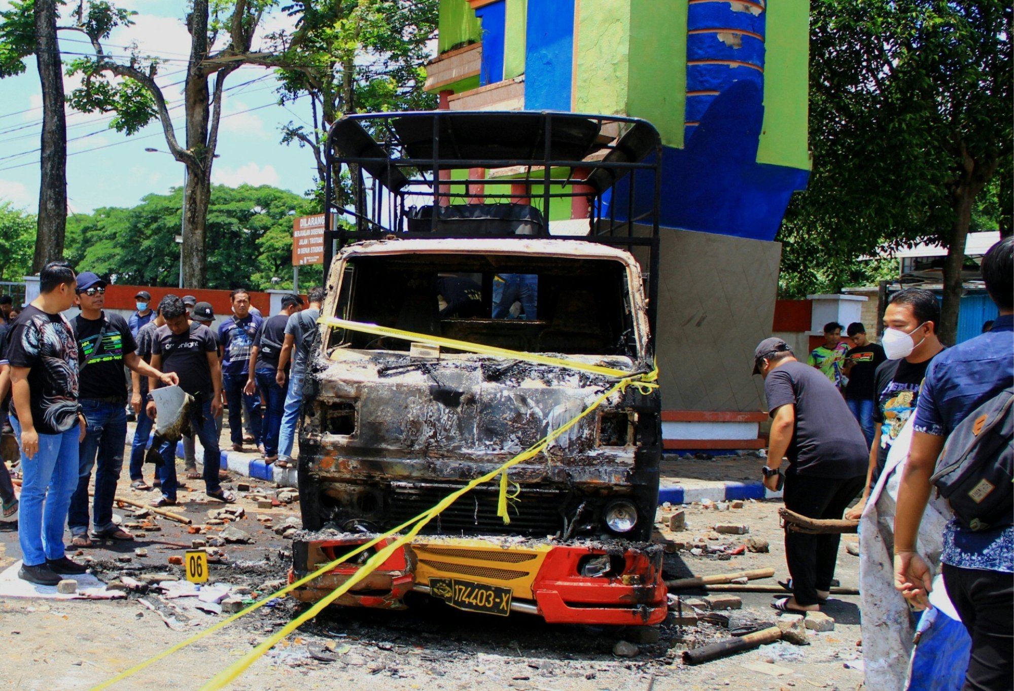 Police conduct an investigation next to a torched vehicle outside the Kanjuruhan stadium in Malang, East Java, on Sunday. Photo: AFP