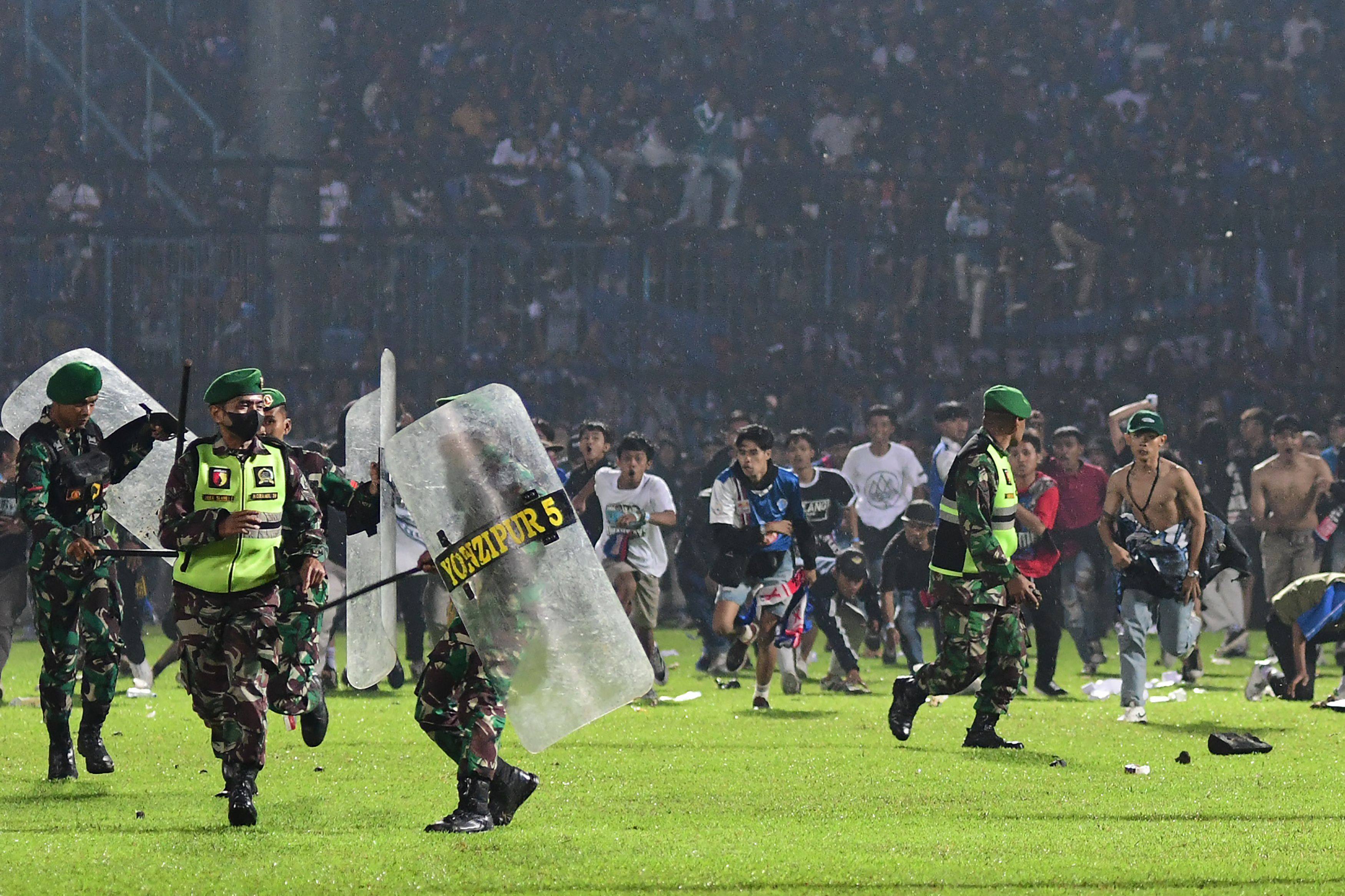 Arema supporters running on the pitch towards Indonesian army personnel after a football match in Malang. Photo: AFP 