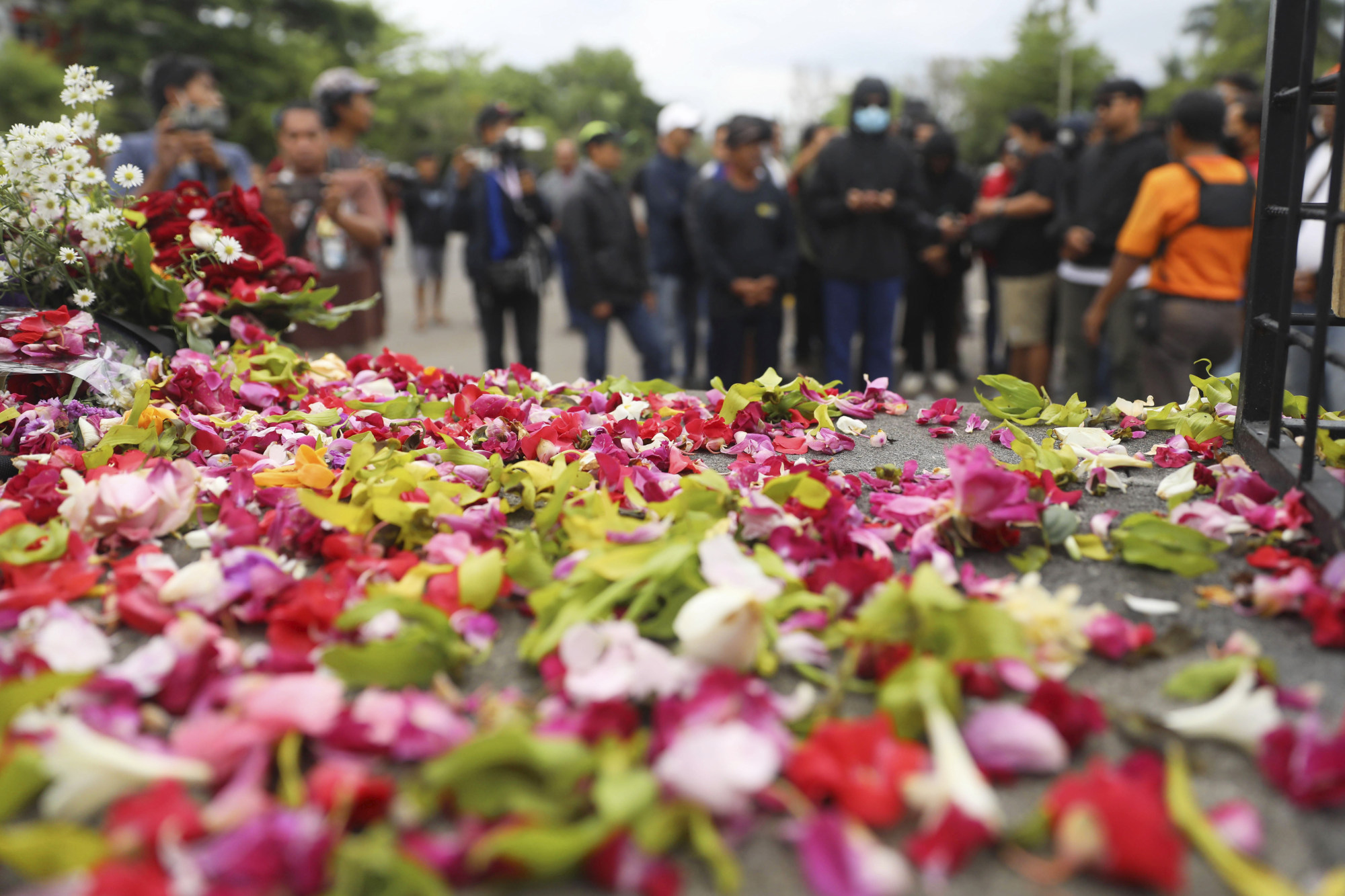 Flowers are sprinkled as supporters of local soccer club Arema FC pray, outside Kanjuruhan Stadium where a soccer match stampede broke out on Saturday night in Indonesia. Photo: AP/File