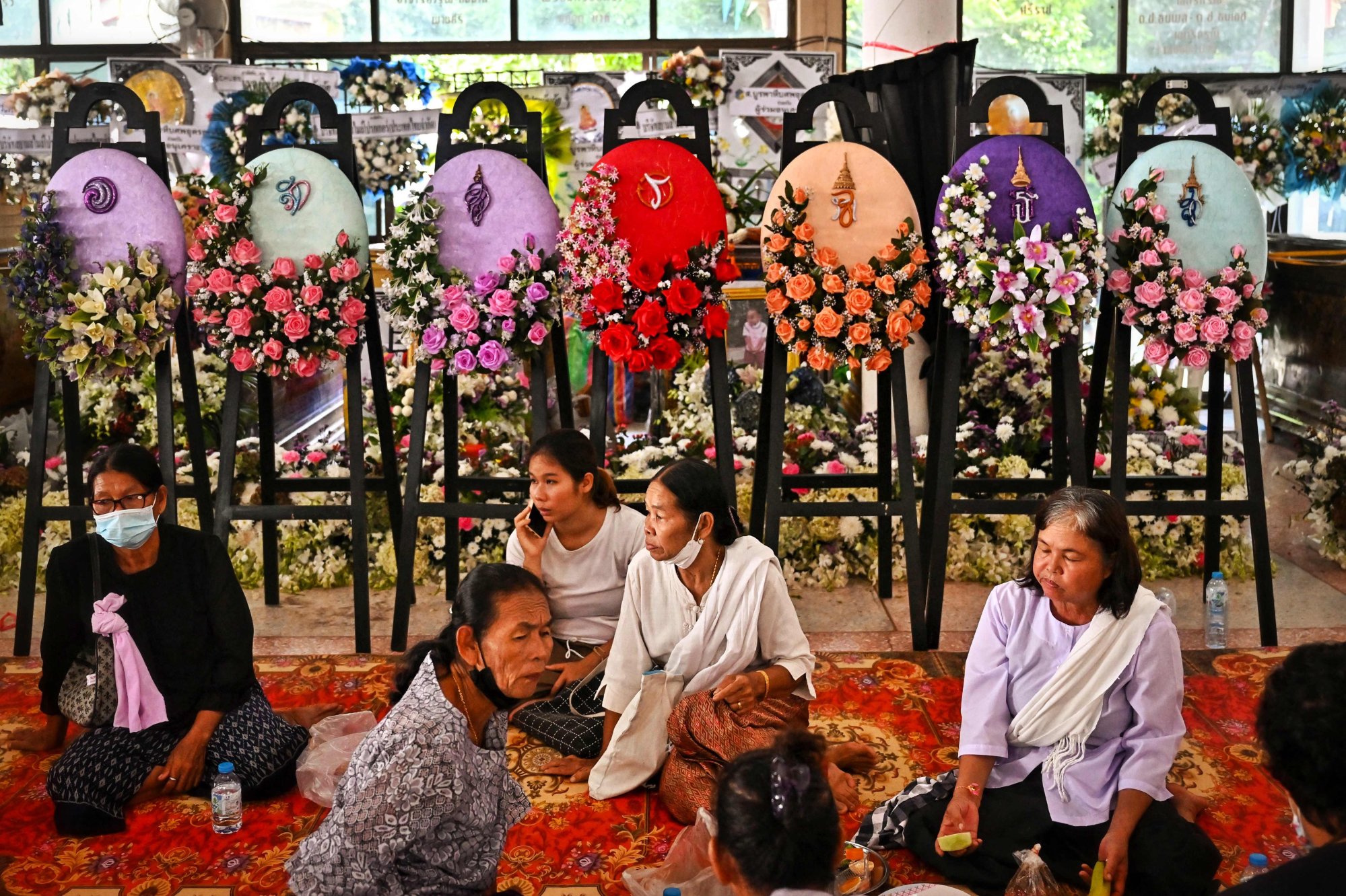 Relatives gather in Thailand on Sunday in front of wreaths and the coffins of victims of Thursday’s mass shooting. Photo: AFP