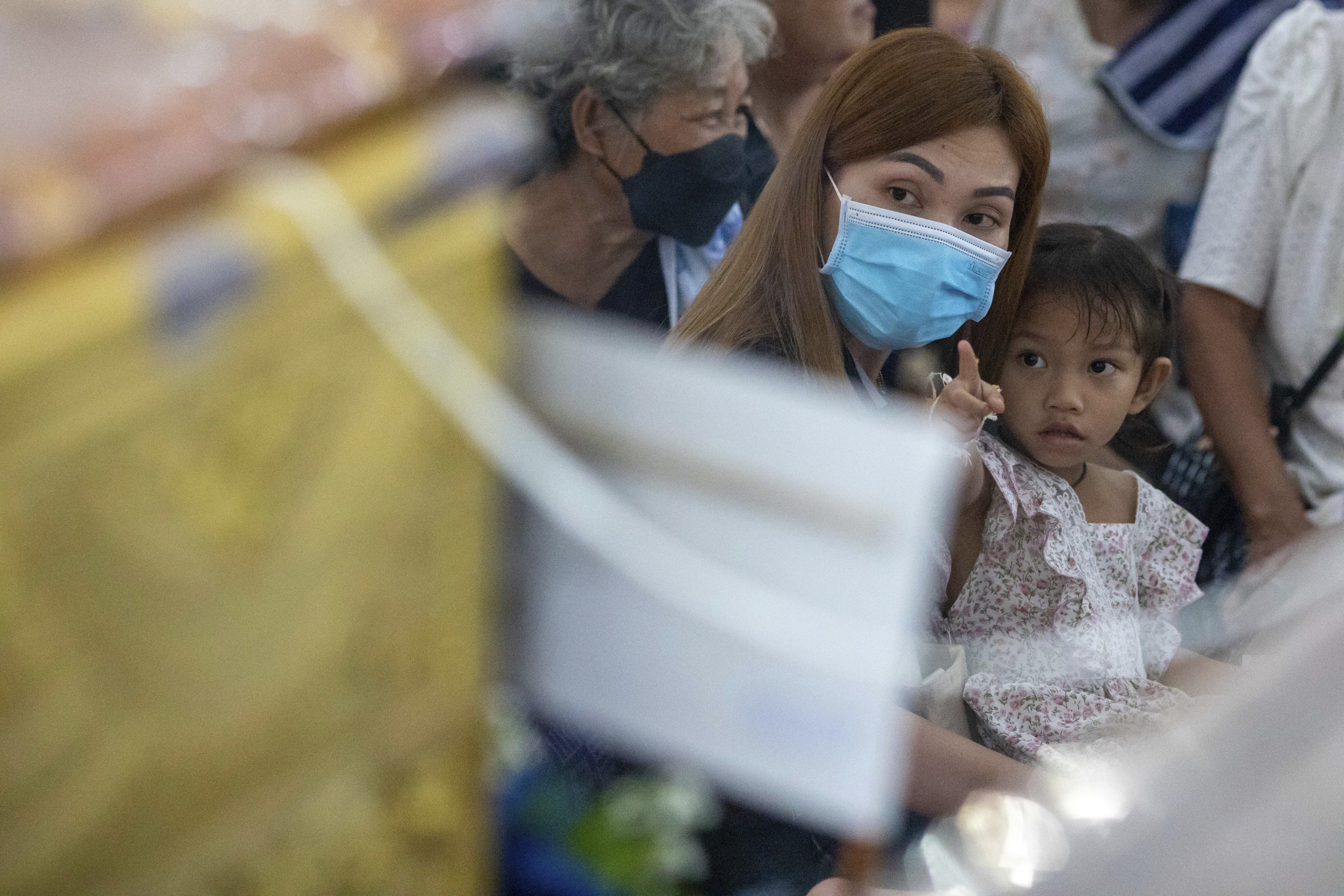Survivor Paweenuch Supolwong, 3, sits with her mother Anonpai Srithong, as she points to the coffin of a friend who was a victim of Thursday’s mass killing in Thailand. Photo: AP