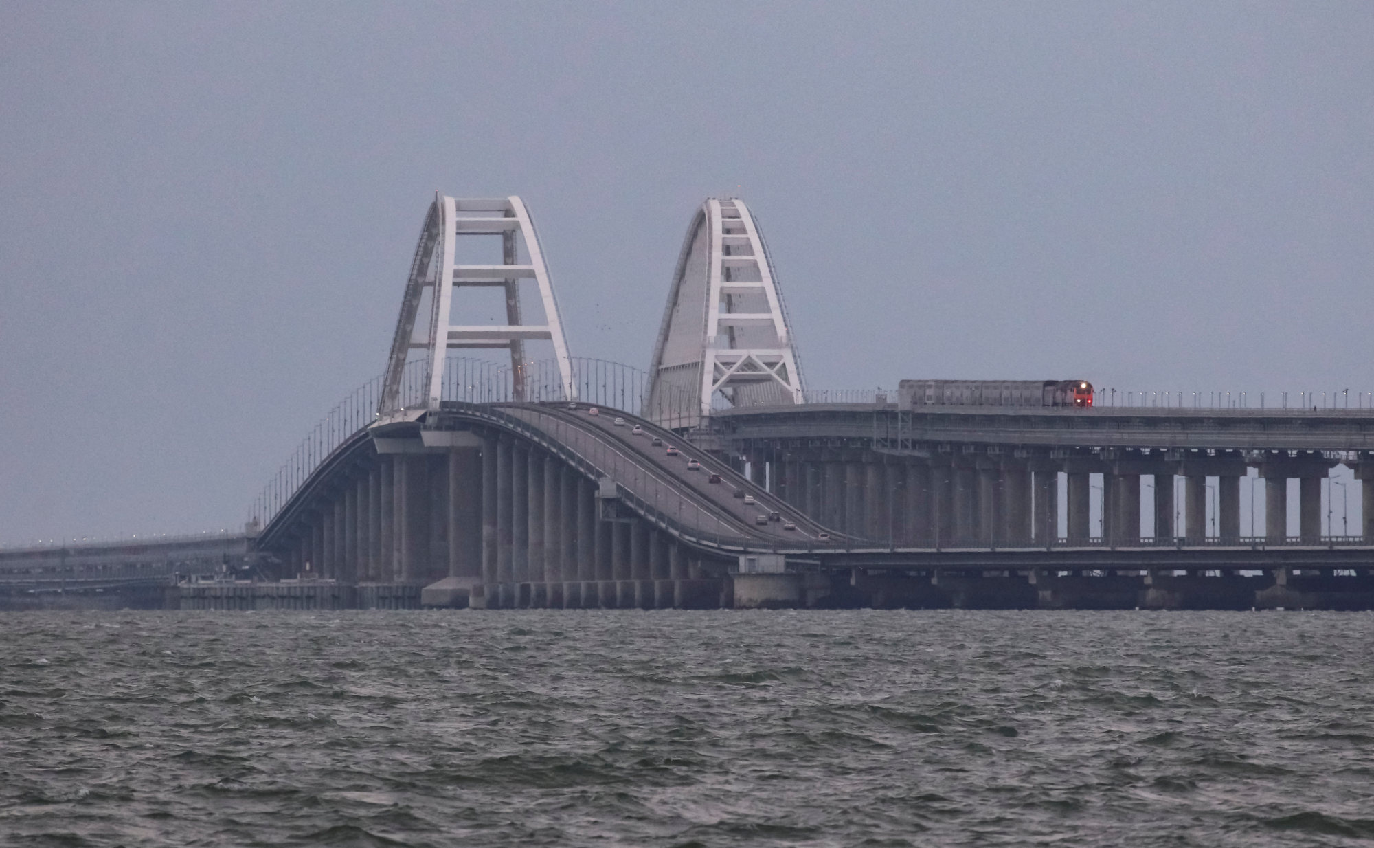 A passenger train and cars drive on the Kerch bridge, after an explosion destroyed part of it. Photo: Reuters