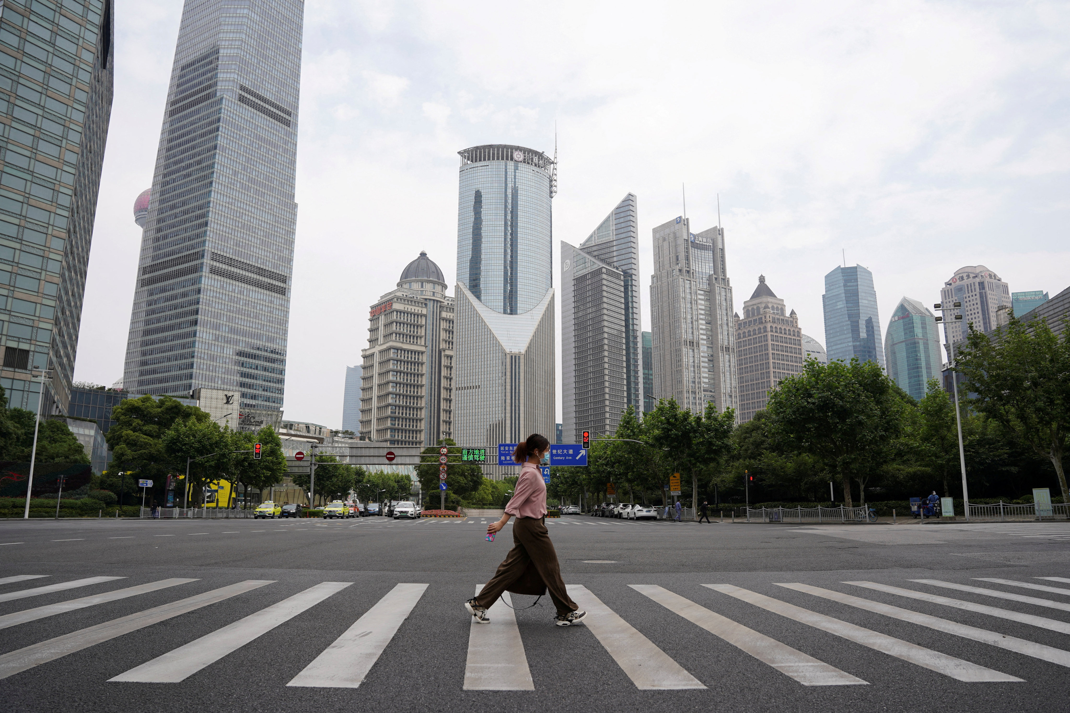 A pedestrian crosses a road in the Lujiazui financial district in Shanghai. Photo: Reuters