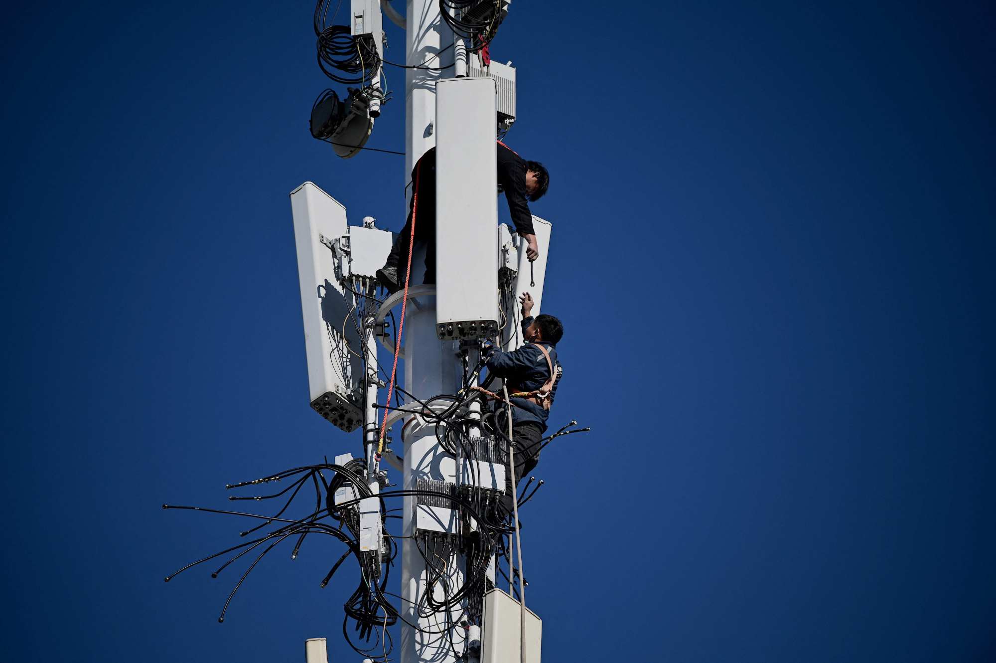 Workers perform maintenance on a 5G tower at Shougang Park in Beijing on December 1, 2021. The energy efficiency of 5G base stations has improved by 20 per cent since the 5G roll-out began in 2019. Photo: AFP