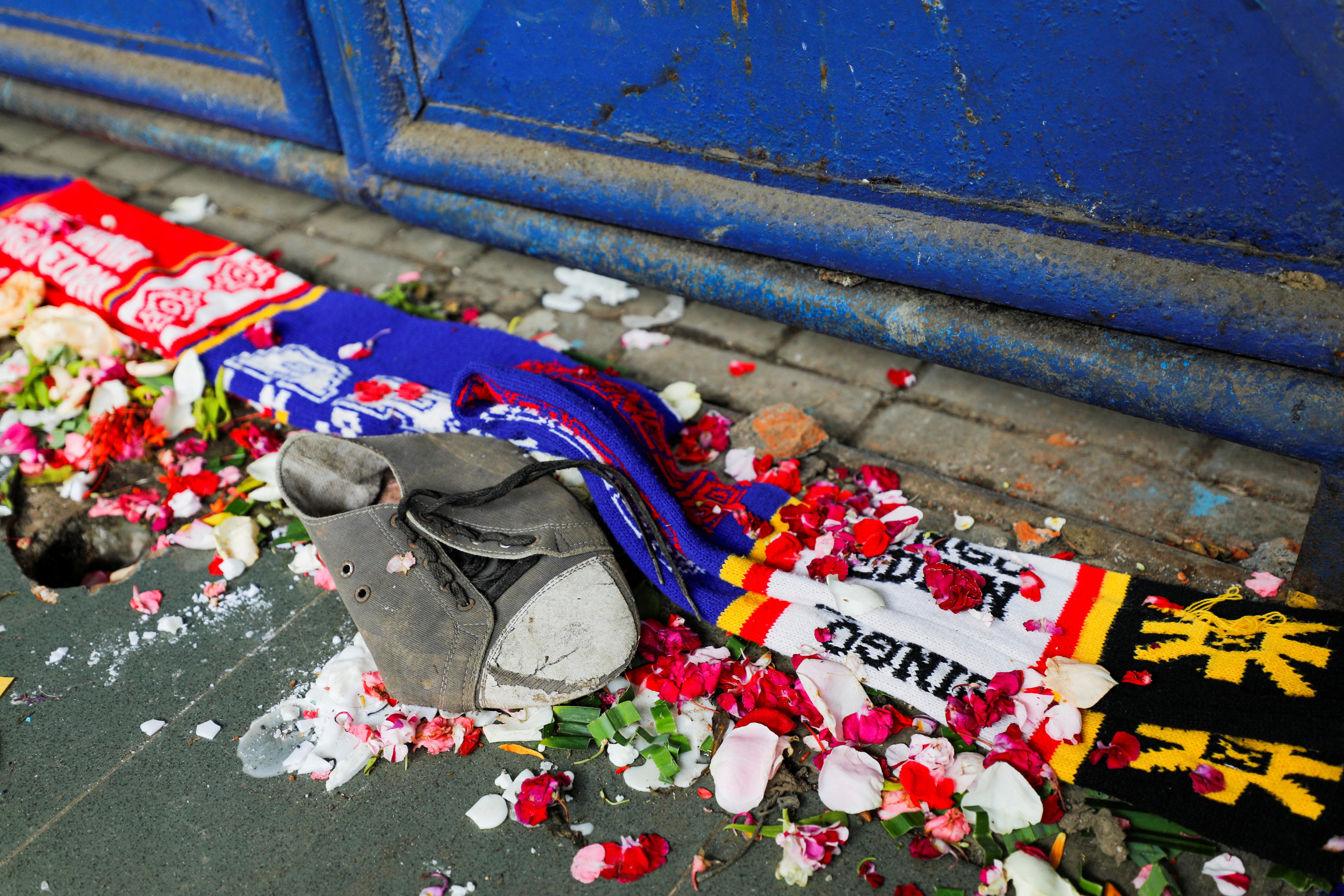 A shoe and soccer scarves are seen among petals near a gate of Kanjuruhan Stadium, after a riot and stampede following soccer match in Indonesia killed at least 130 people. Photo: Reuters/File