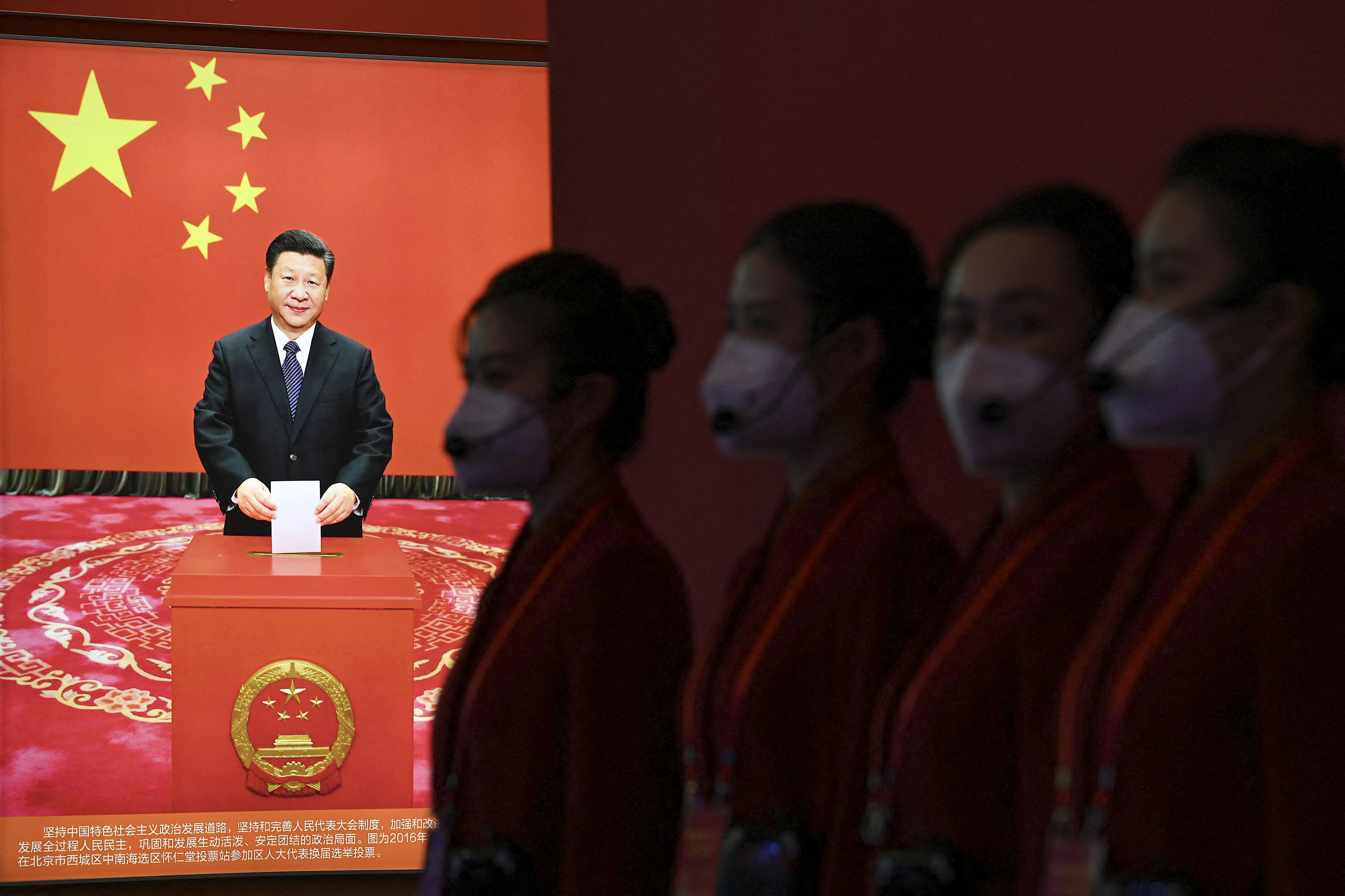 Attendants stand near a picture of Chinese President Xi Jinping at the Beijing Exhibition Centre, ahead of the 20th Communist Party Congress. Photo: AFP