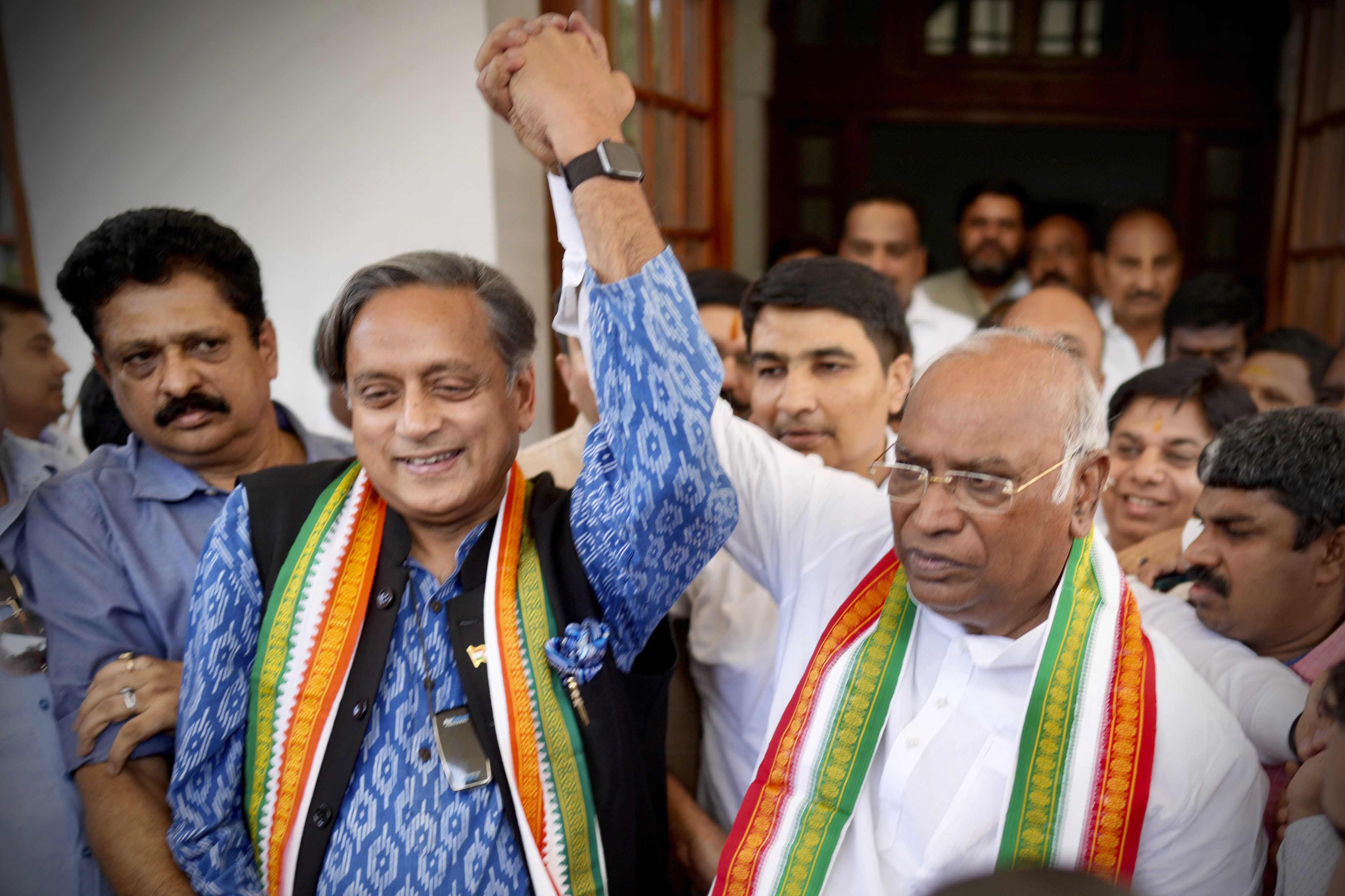 Newly elected Congress Party president Mallikarjun Kharge, right,  raises hands with party leader Shashi Taroor. Photo: AFP