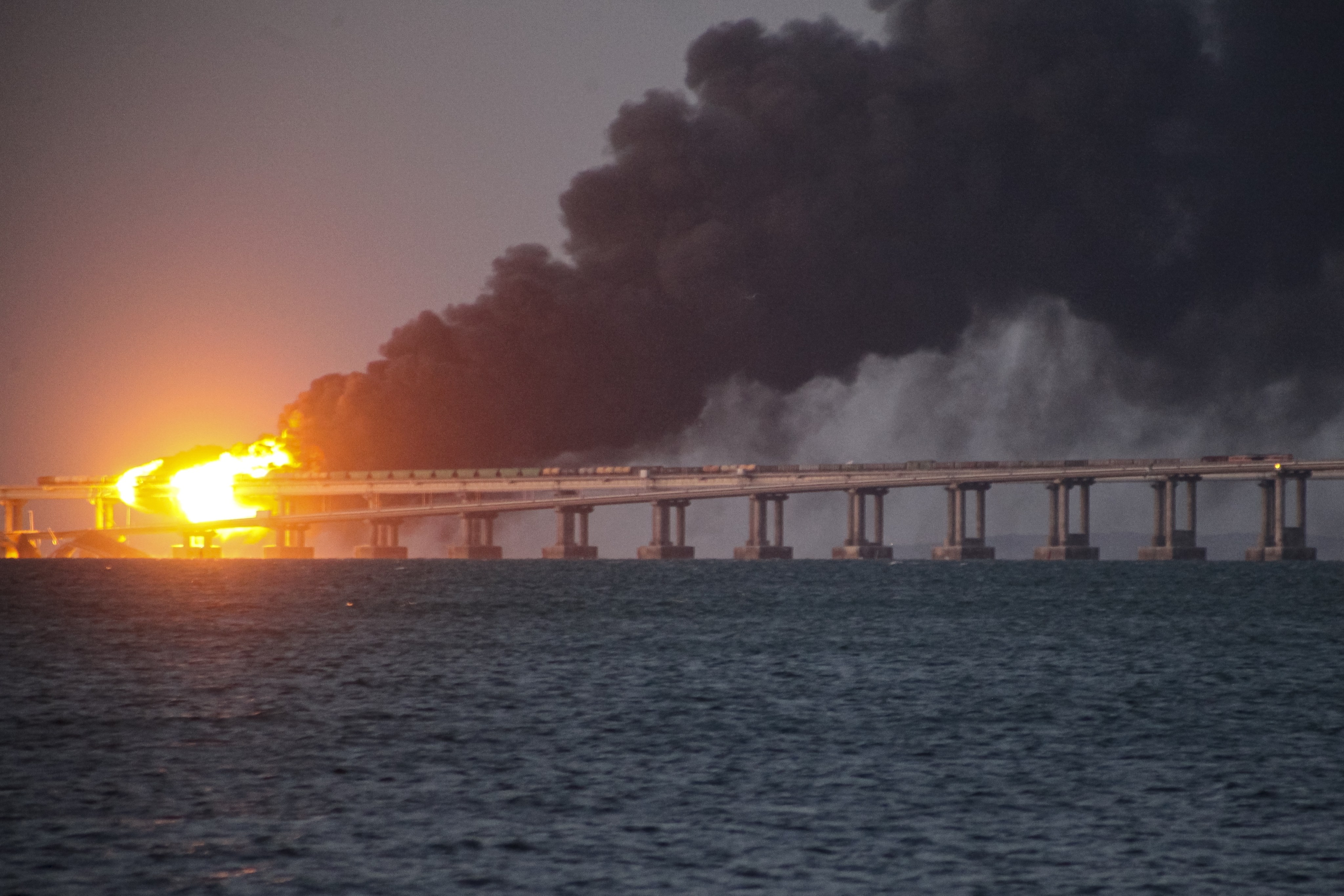 Flames and smoke rise from the Crimean Bridge connecting the Russian mainland and Crimean peninsula on October 8, 2022. Russian authorities blamed a truck bomb. Photo: AP