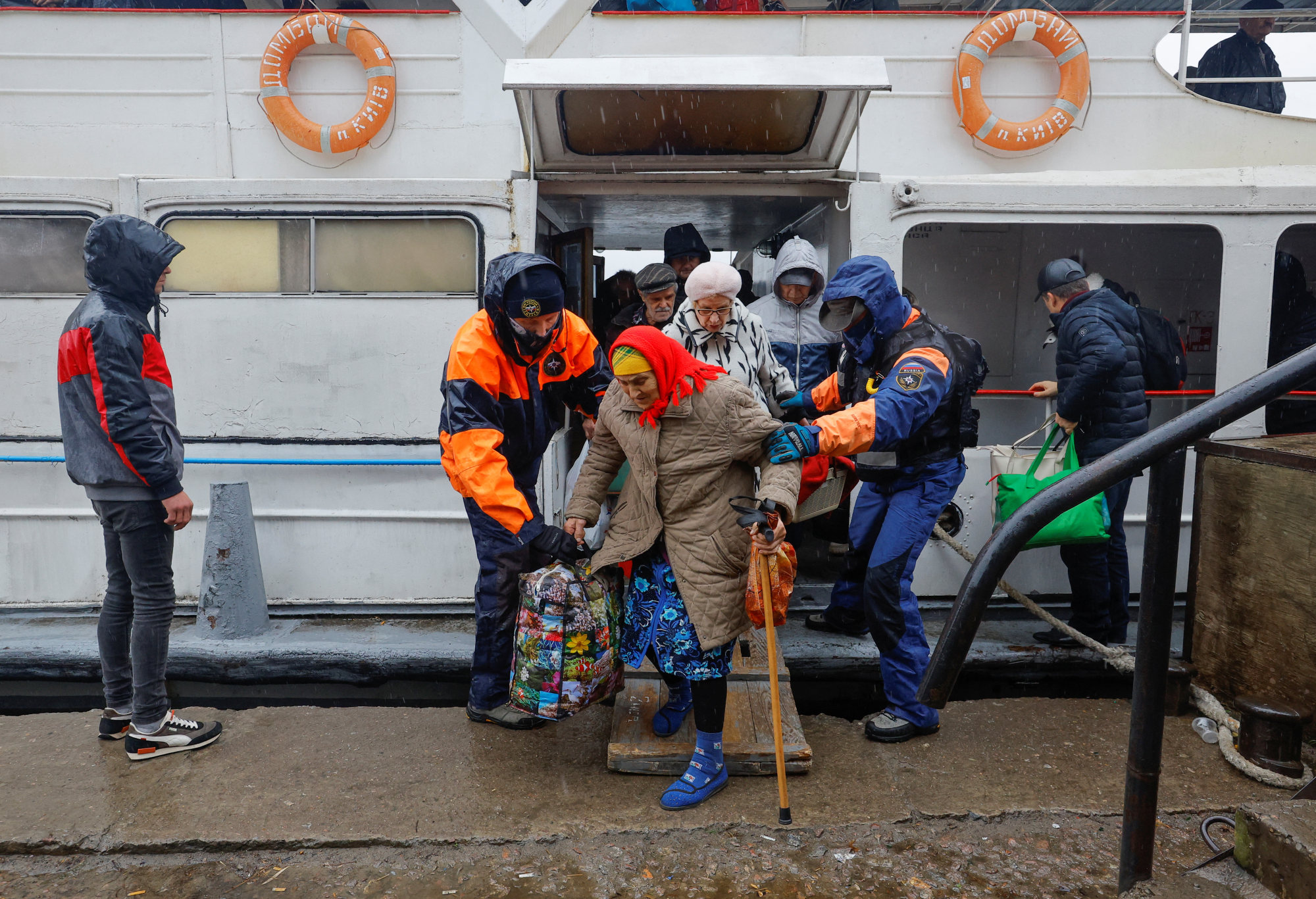 Civilians evacuated from the Russian-controlled city of Kherson walk from a ferry to board a bus heading to Crimea, in the town of Oleshky, on Sunday. Photo: Reuters