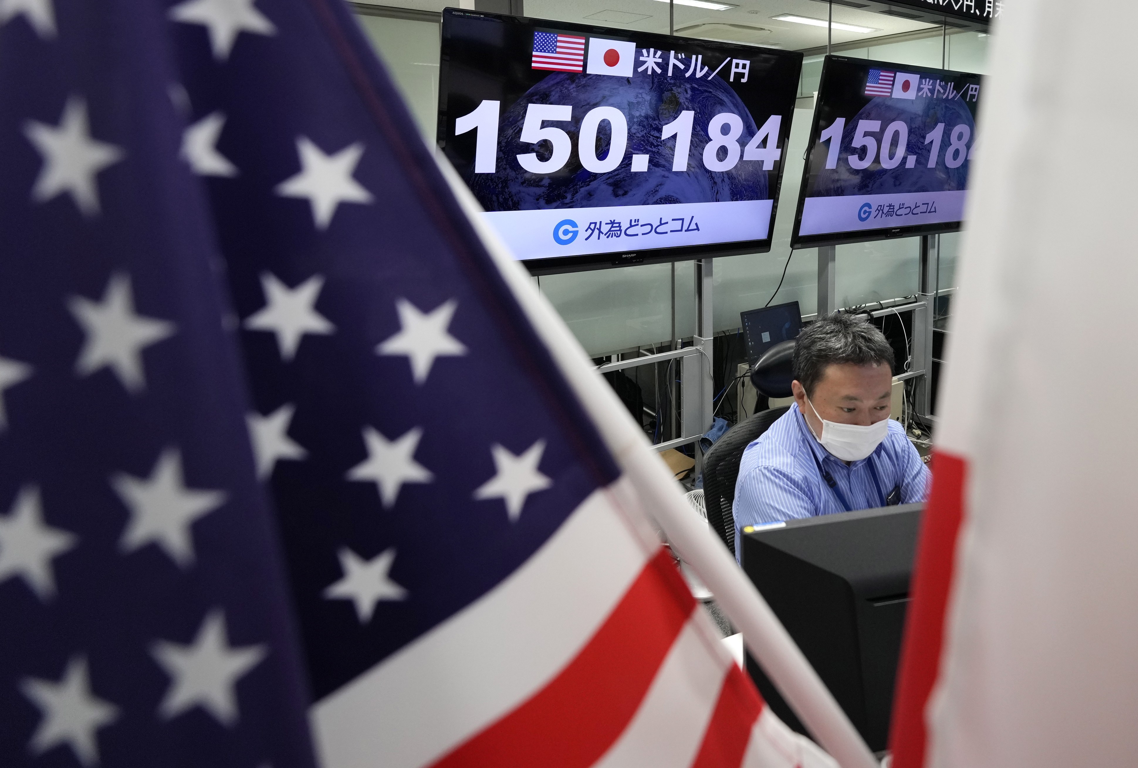A dealer works as displays show the exchange rate between the Japanese yen and the US dollar at a foreign exchange trading company in Tokyo on October 21. The yen continues its fall against the US dollar, hitting a 32-year low, to remain in the 150 range. Photo: EPA-EFE